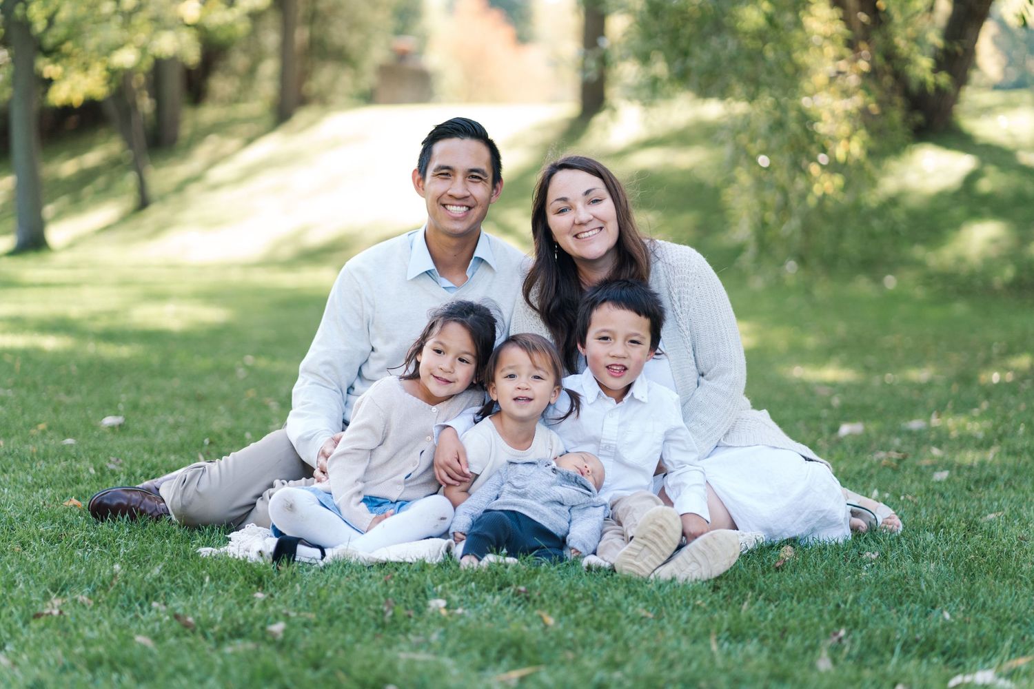 Family lounging together on grassy hillside during outdoor photo session.
Niagara family photos.