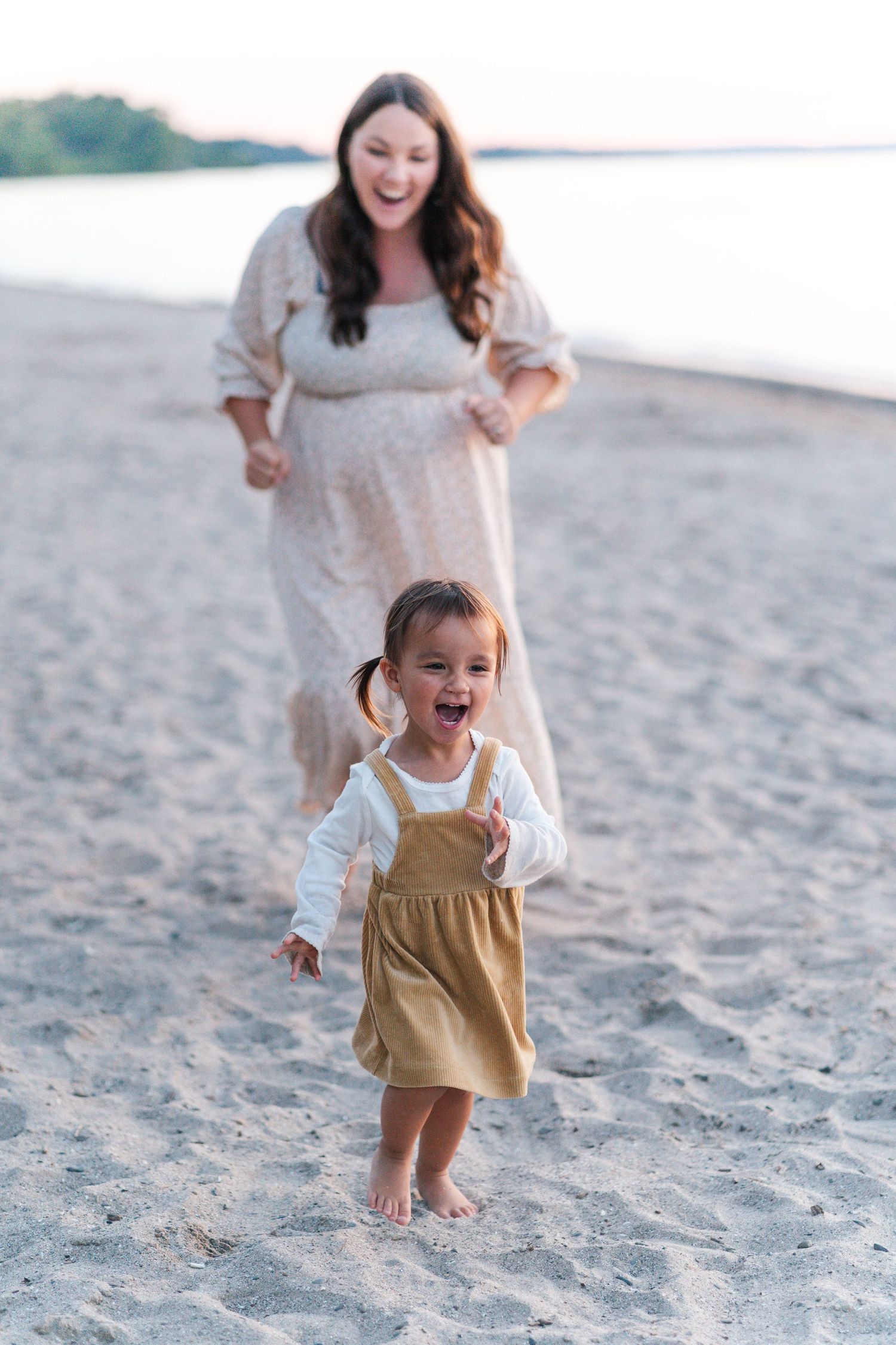 A joyful toddler in overalls plays and runs on a sandy beach during sunset.
Niagara family photos