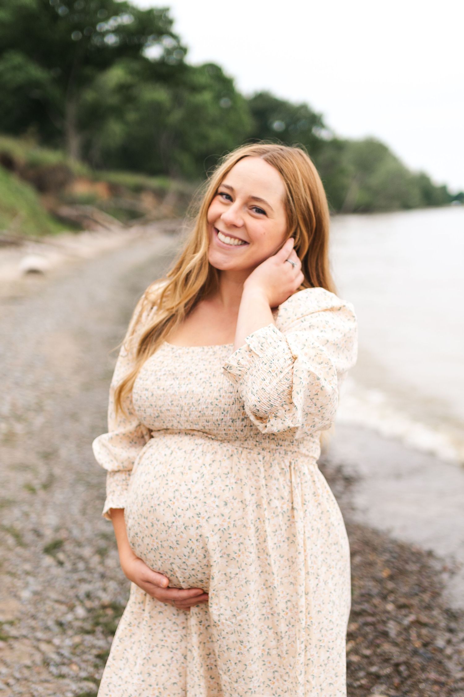 Expectant mother in a floral dress posing on a rocky beach during a maternity photoshoot.
Niagara maternity photos.