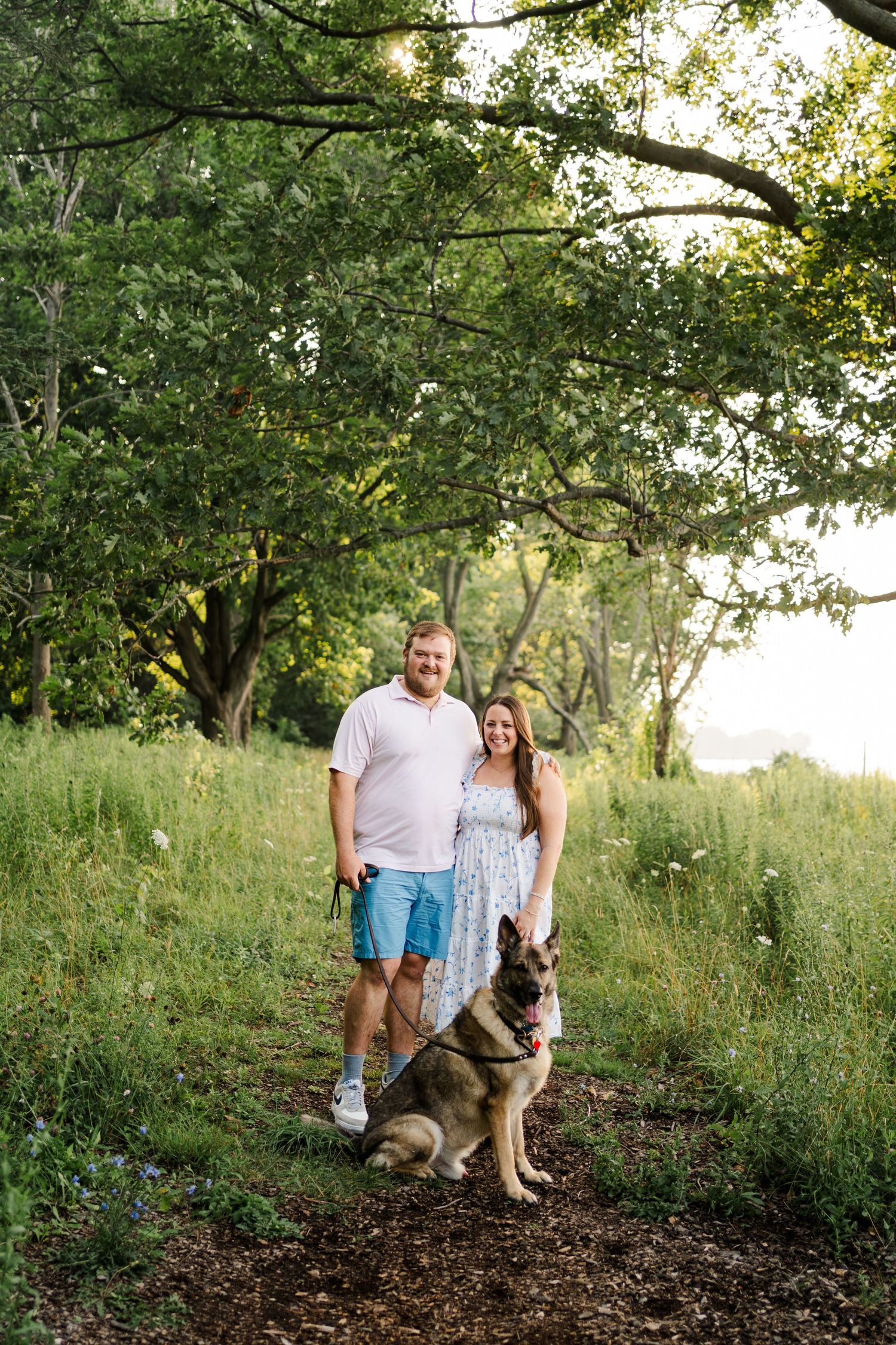 Couple walks their German Shepherd dog along a tree-lined trail during a summer evening.
Niagara family photos