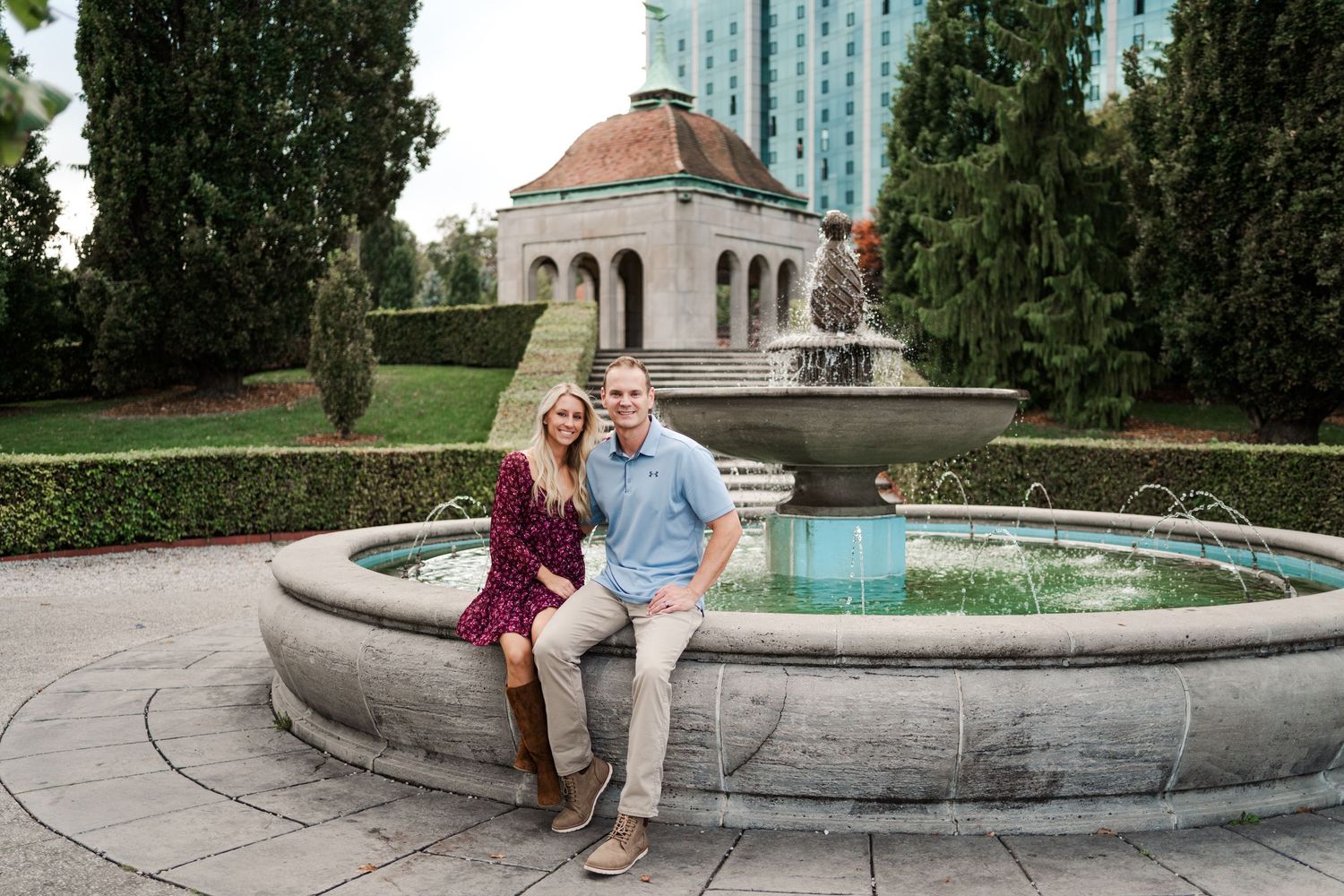 Couple sitting together by a decorative fountain in an urban park setting.
Niagara couple photos.