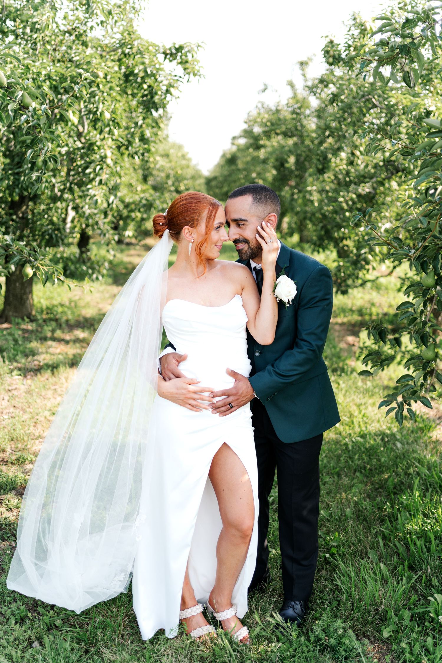 Newlyweds share romantic moment in orchard with flowing wedding dress.
Wedding in Niagara.