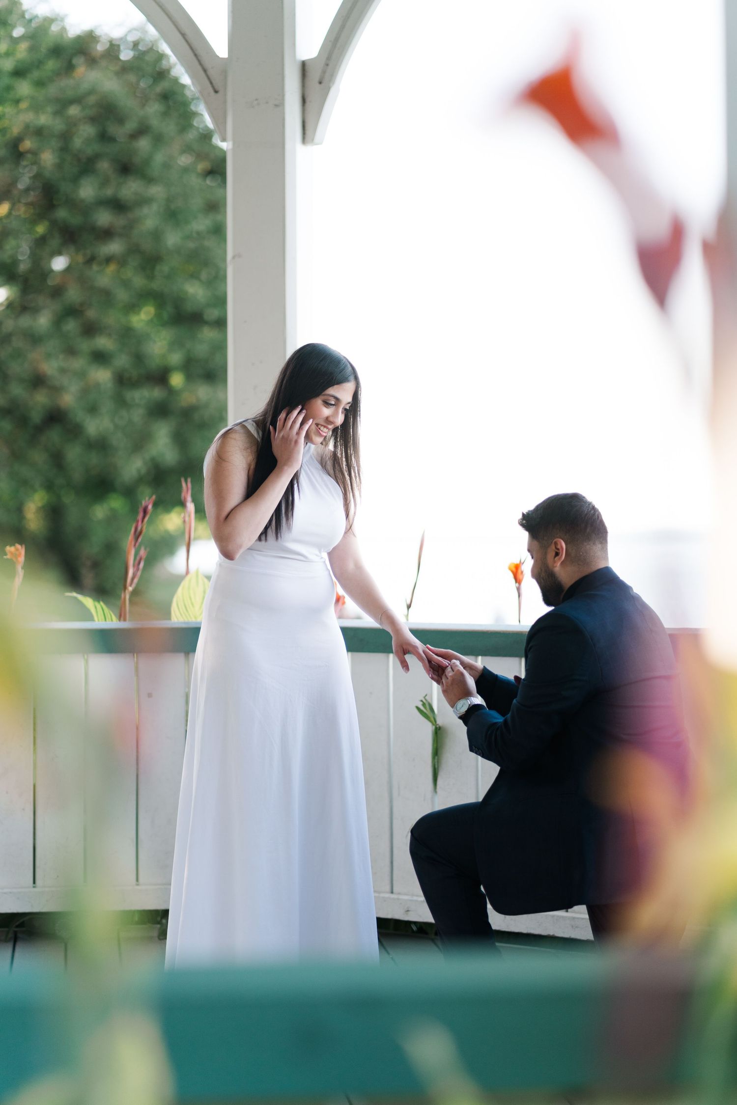 A surprise proposal moment under a white pergola with blurred decorations in the background.
Niagara proposal photos.