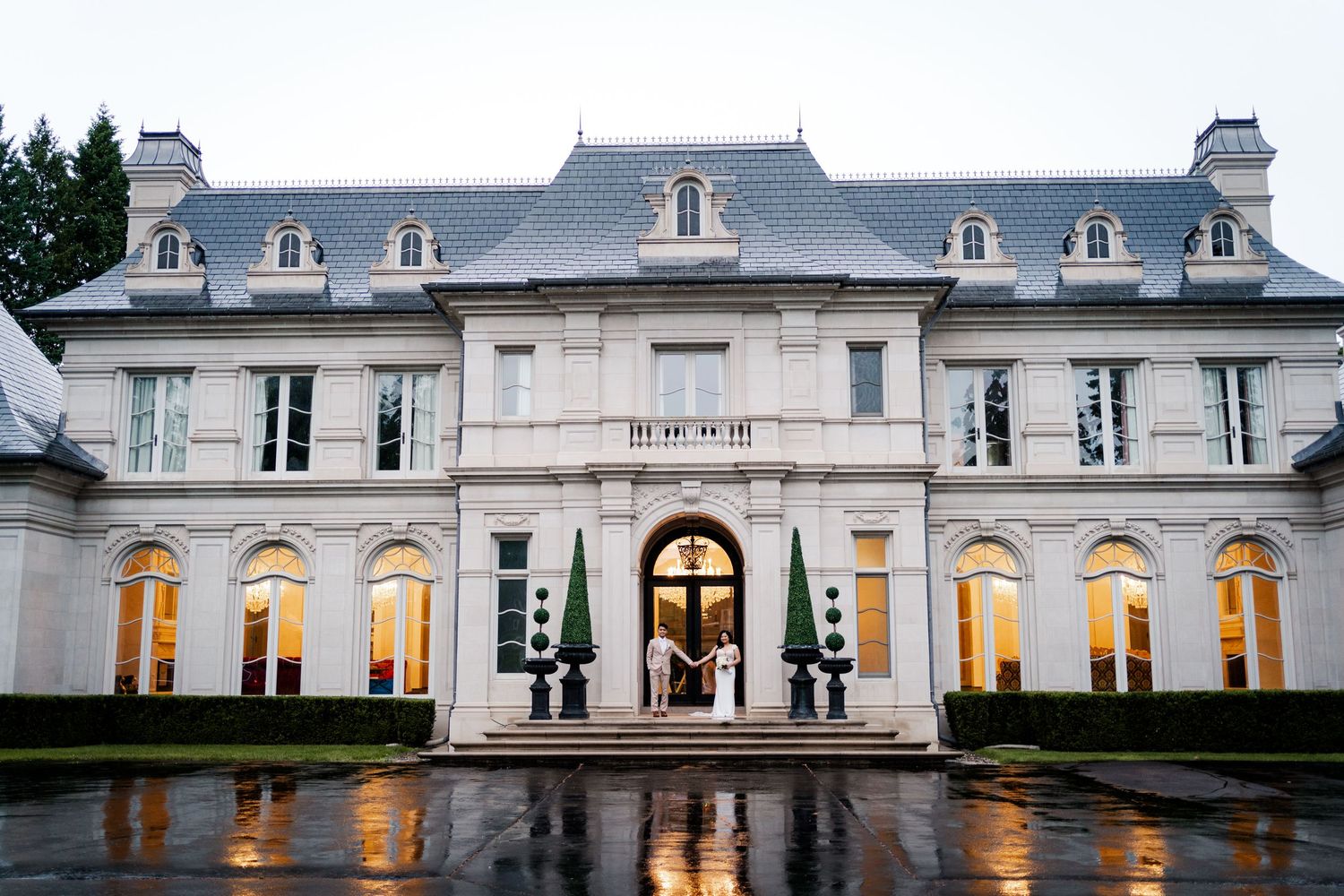 Grand white mansion with illuminated entrance and reflecting pool at dusk.
Toronto wedding photos.