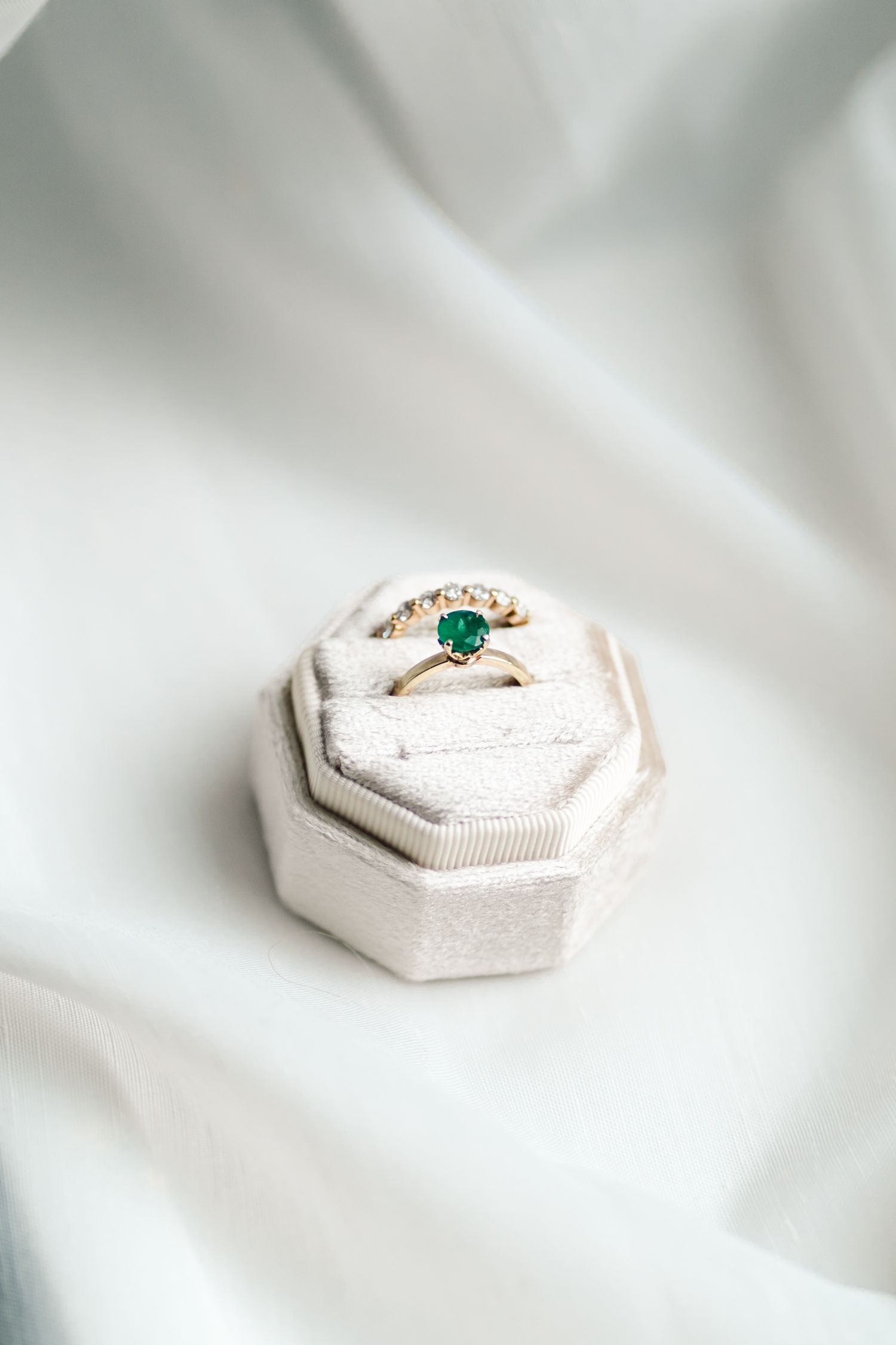 Vintage-style emerald ring nestled in cream hexagonal ring box on white fabric.
Niagara Wedding photography.