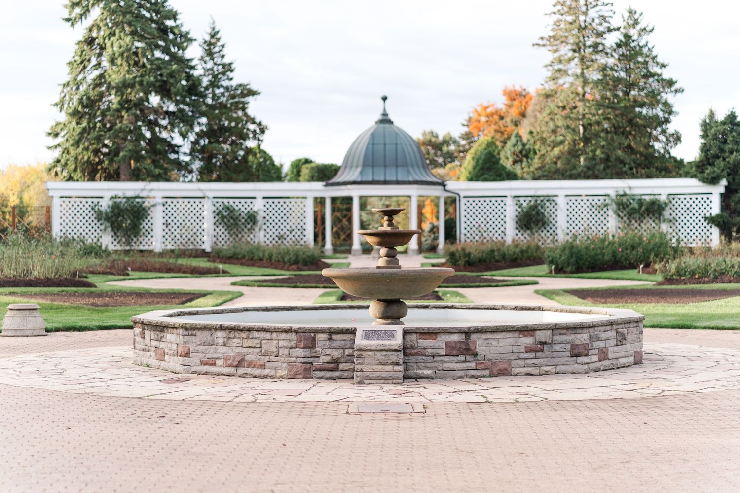 A scenic garden fountain with white lattice walls and domed gazebo in the background.
Niagara engagement photos.