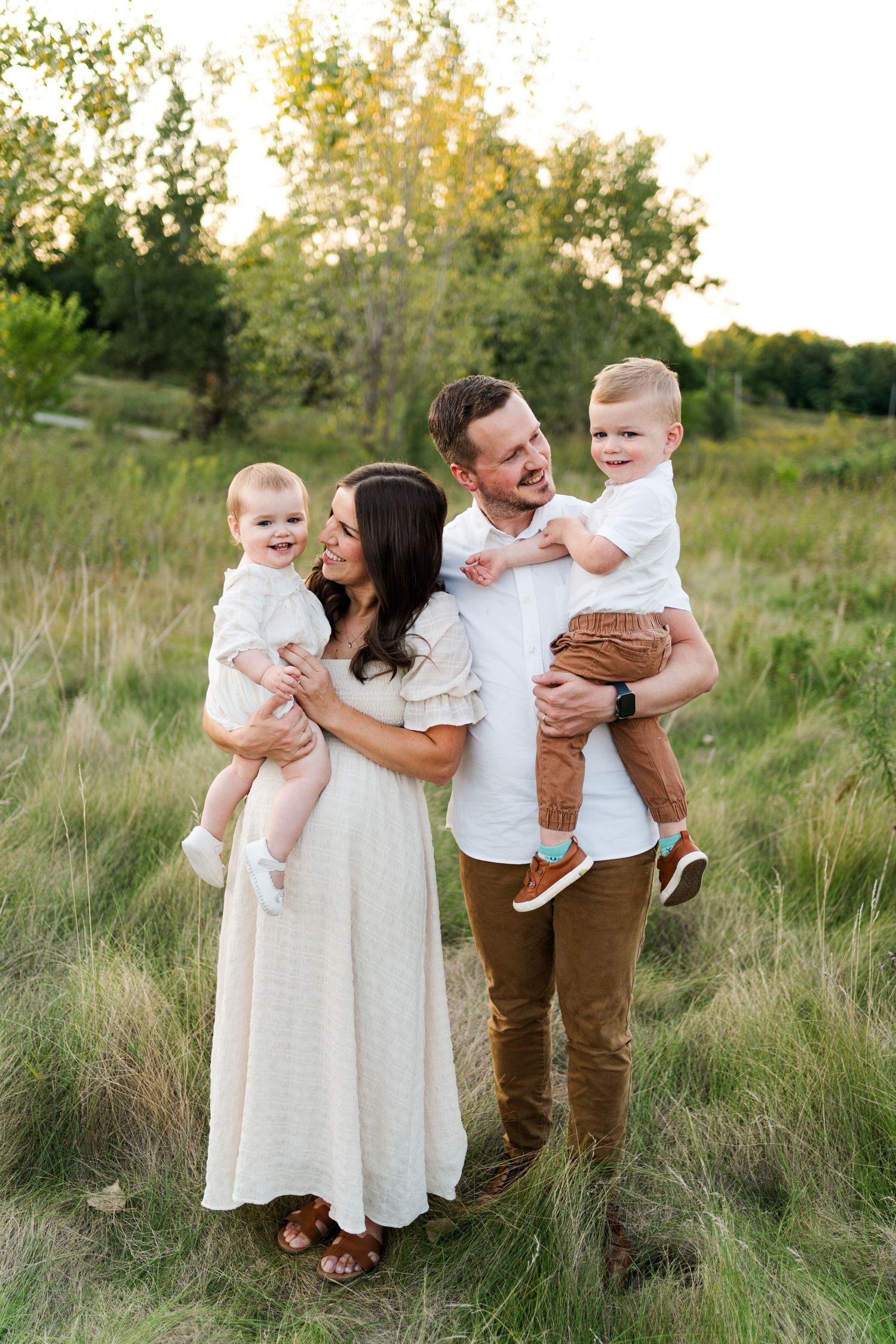 A family of four poses together in casual attire against a backdrop of tall grass at golden hour.
Family photos in Niagara