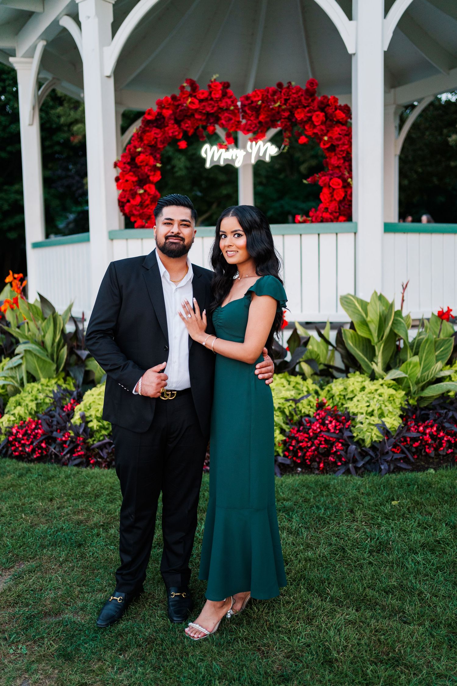 Newly engaged couple posing in front of red floral heart arch.
Niagara Proposal.