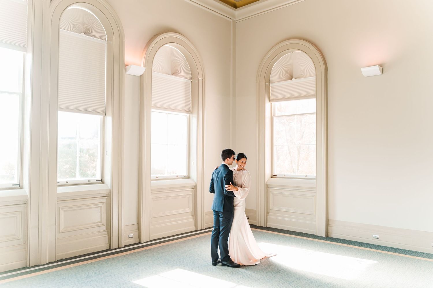 A couple shares an intimate moment in an elegant room with arched windows and natural light.
Wedding in Niagara.