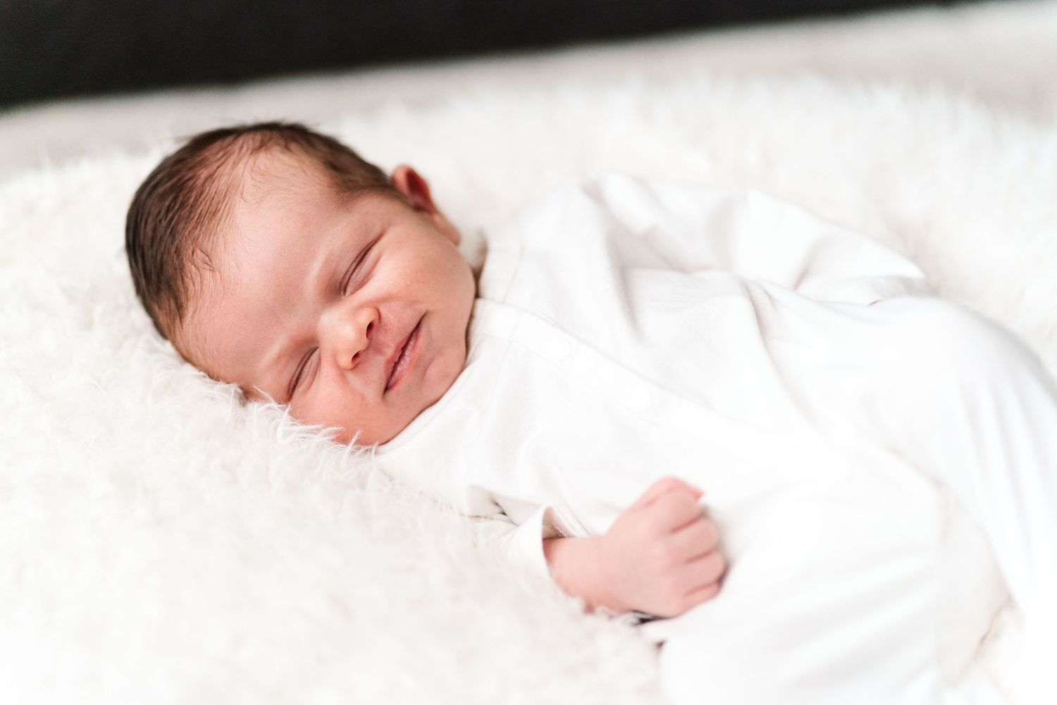 Newborn baby sleeping peacefully on white bedding in natural light.
Niagara newborn photos.