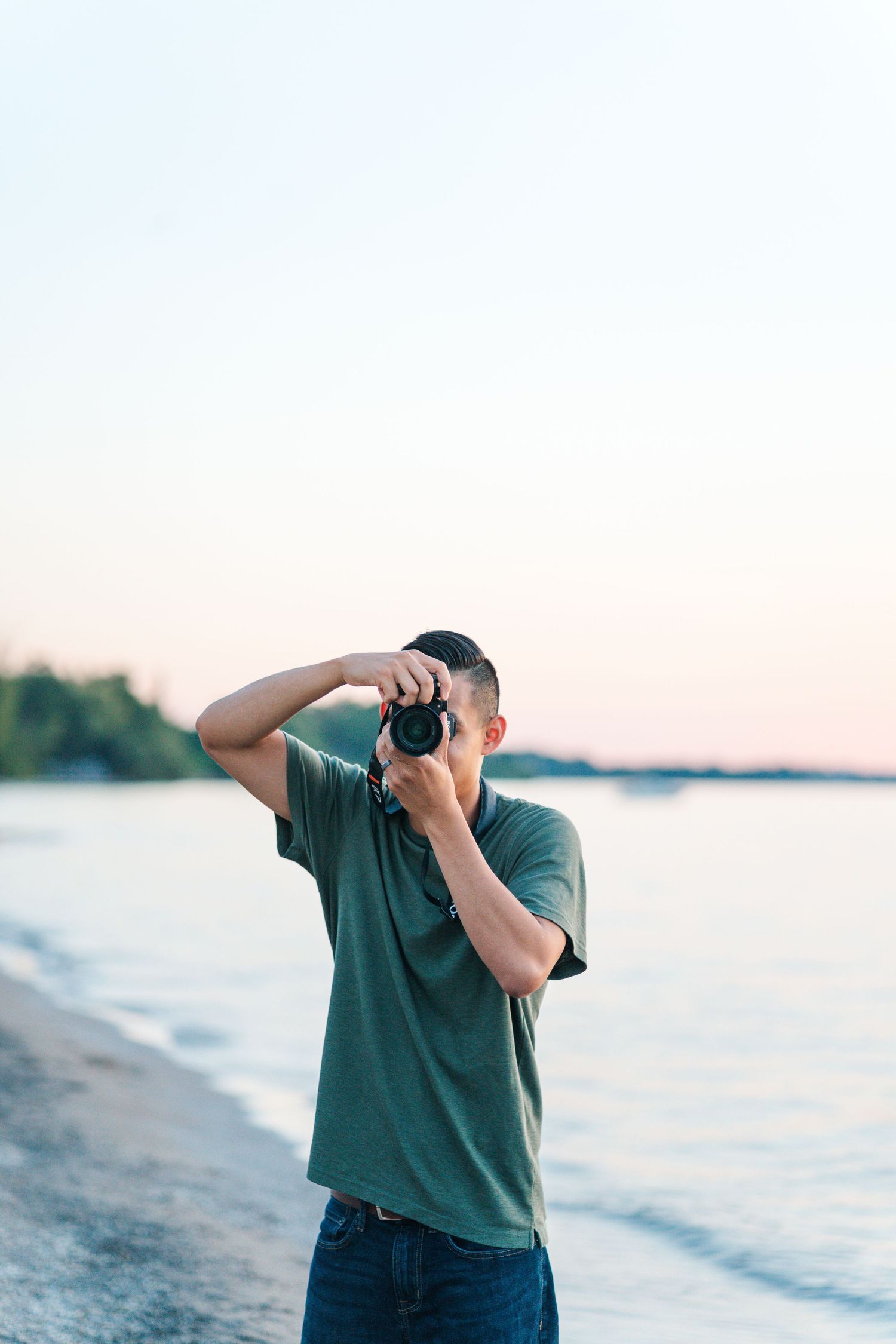 A photographer in a green shirt takes pictures while standing on a beach at sunset.
Niagara familly photos.