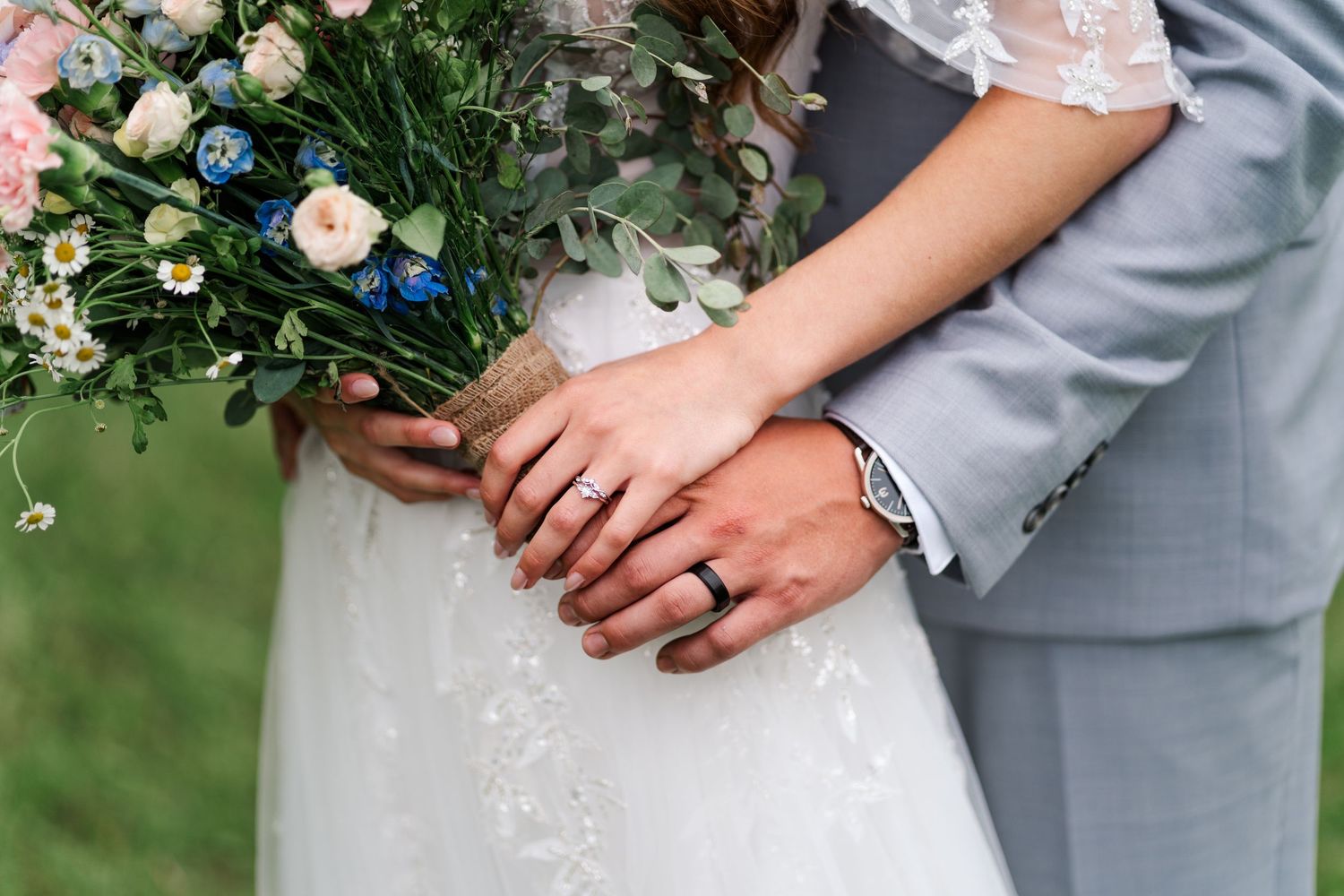 A bride in a white lace dress holds a delicate bouquet of pink and white flowers during an outdoor wedding ceremony.
Wedding in Niagara.