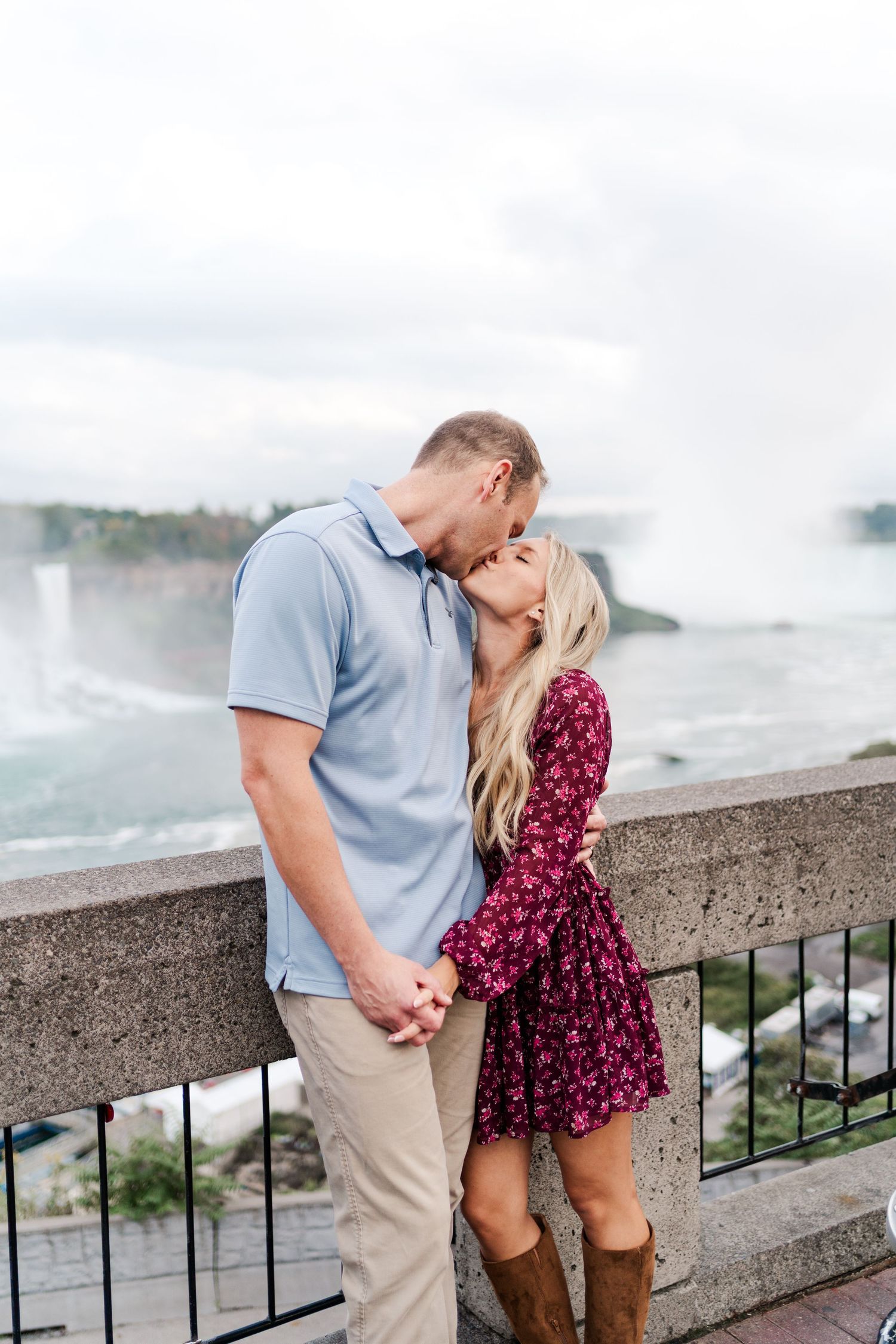 A romantic couple shares an intimate moment by a railing overlooking Niagara Falls.
Niagara engagement photos.