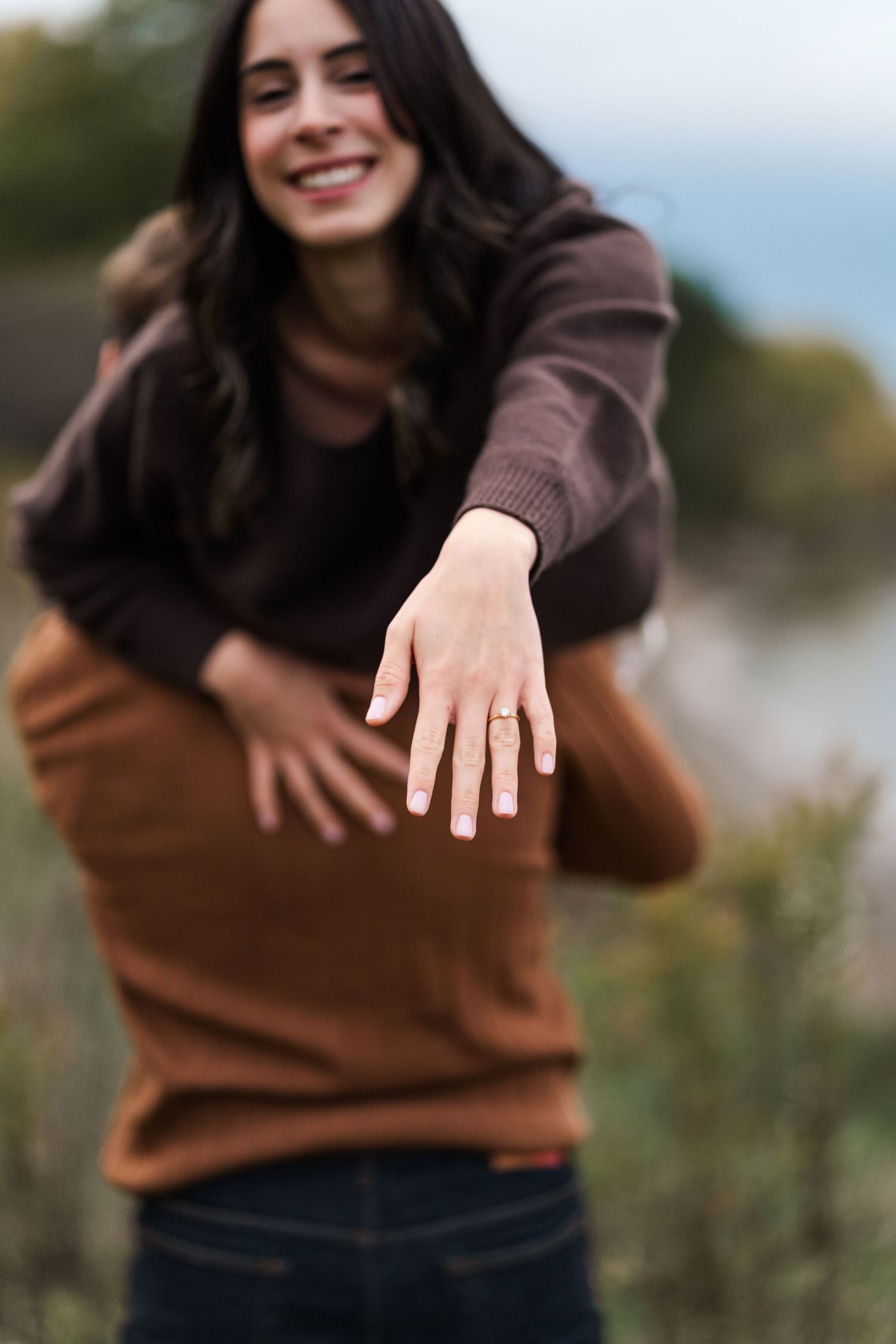 Woman in brown sweater showing off her engagement ring in an outdoor setting.
Niagara engagement photos.