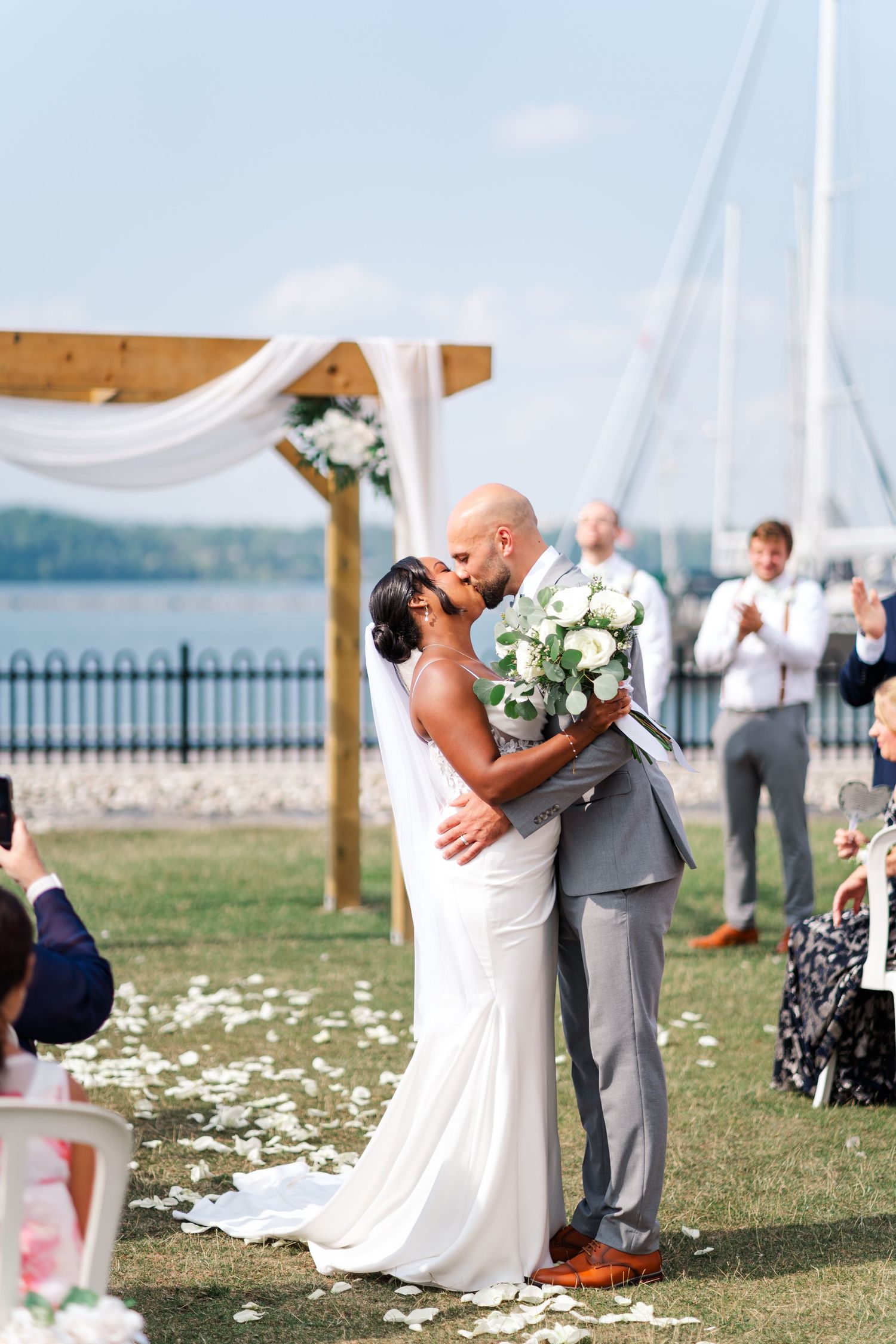 Wedding ceremony kiss under white draped arch by waterfront.
Niagara wedding photos.