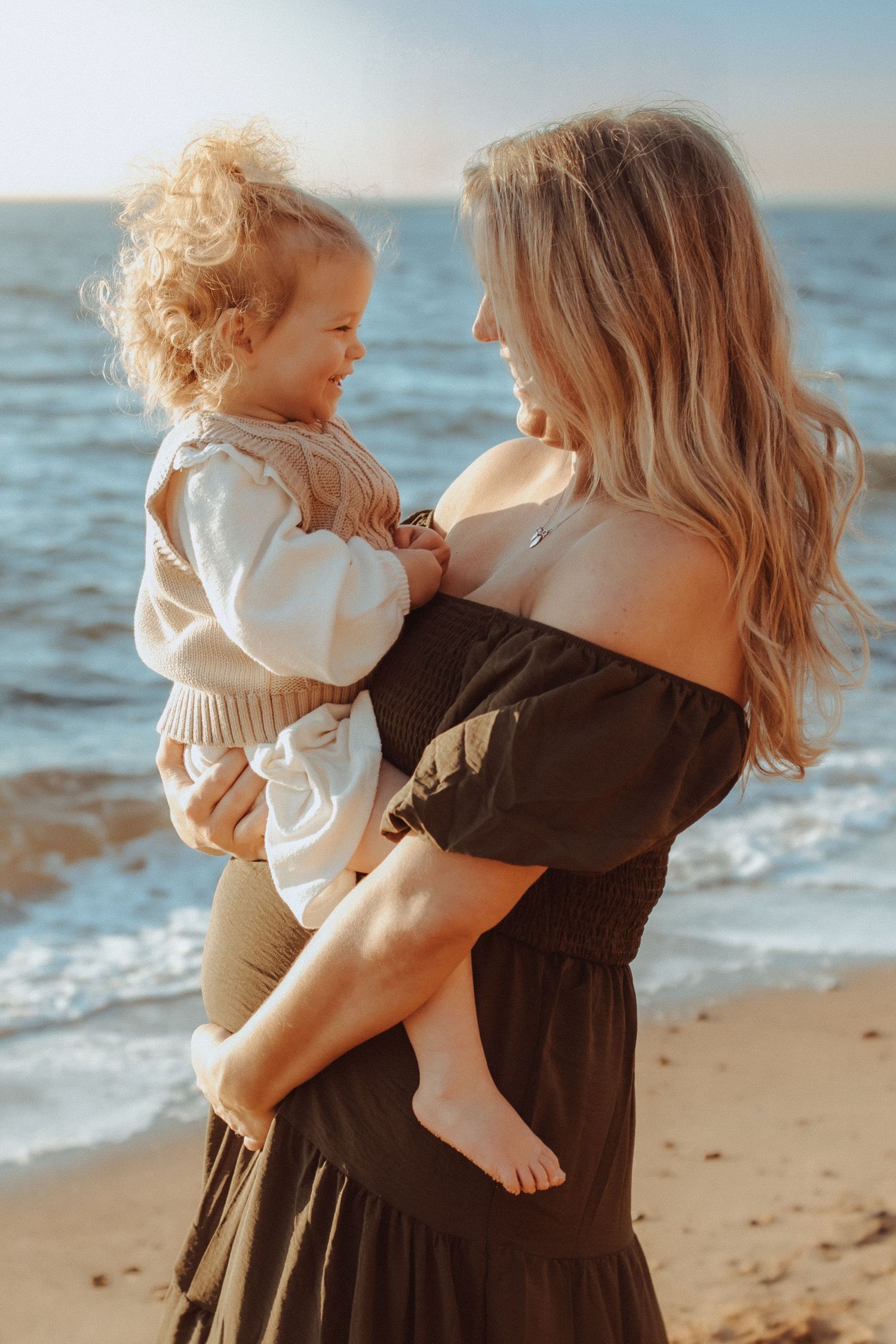 Mother and toddler sharing tender moments together on a sunny beach.