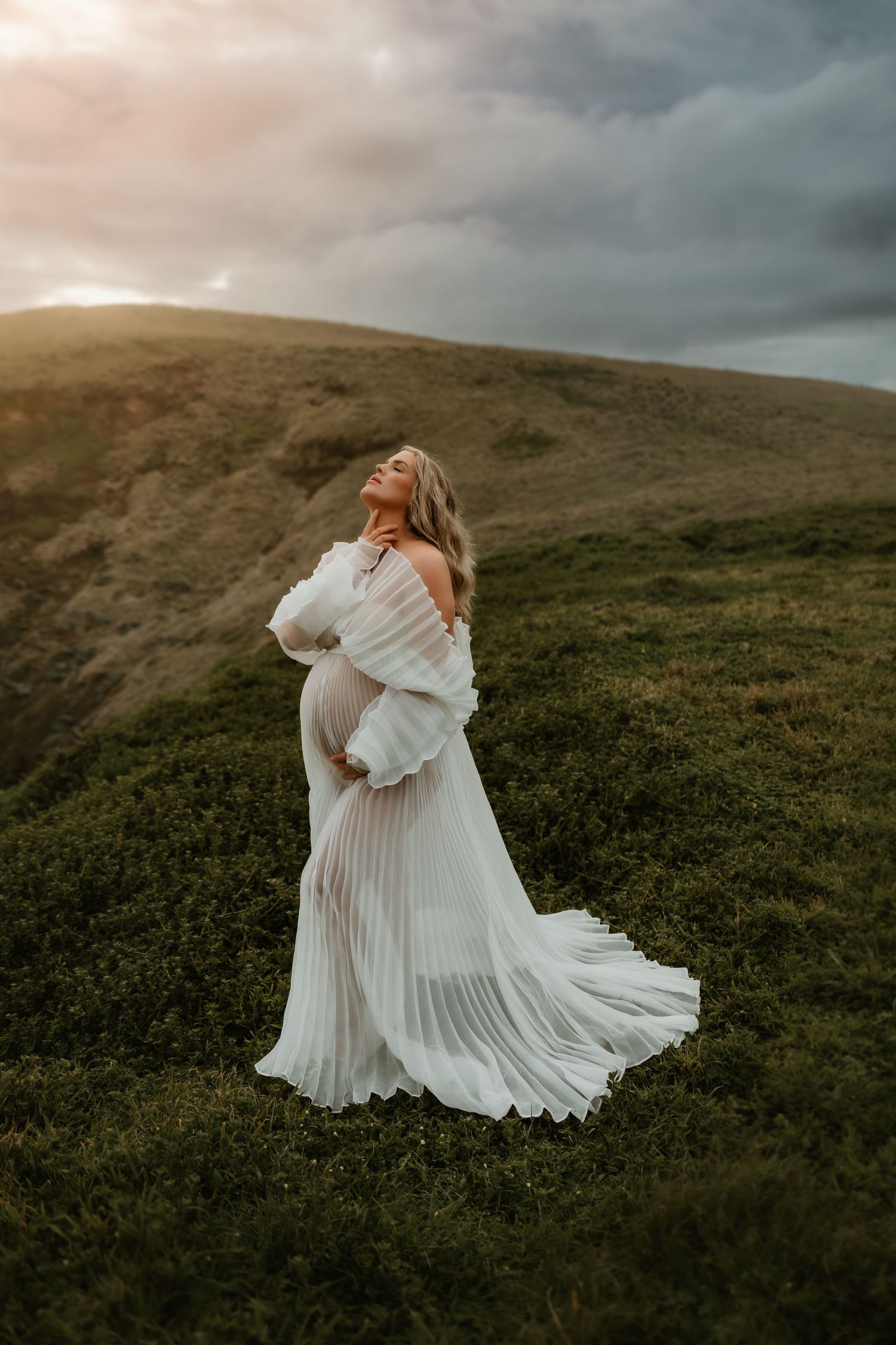 Flowing white dress twirls dramatically against rolling green hillside landscape.