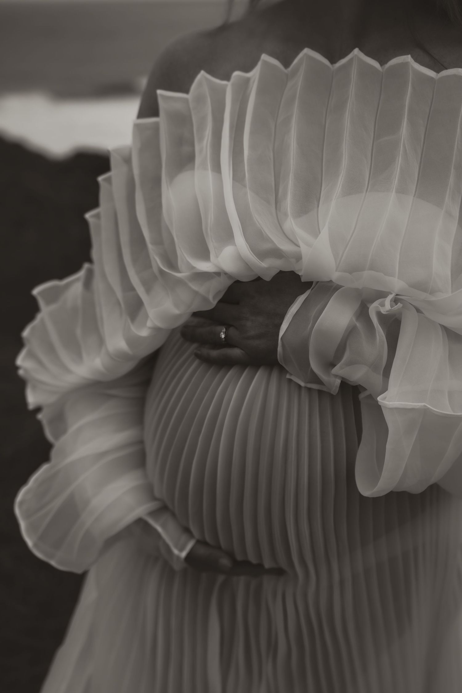 Close-up detail of delicate pleated ruffles on white formal dress.