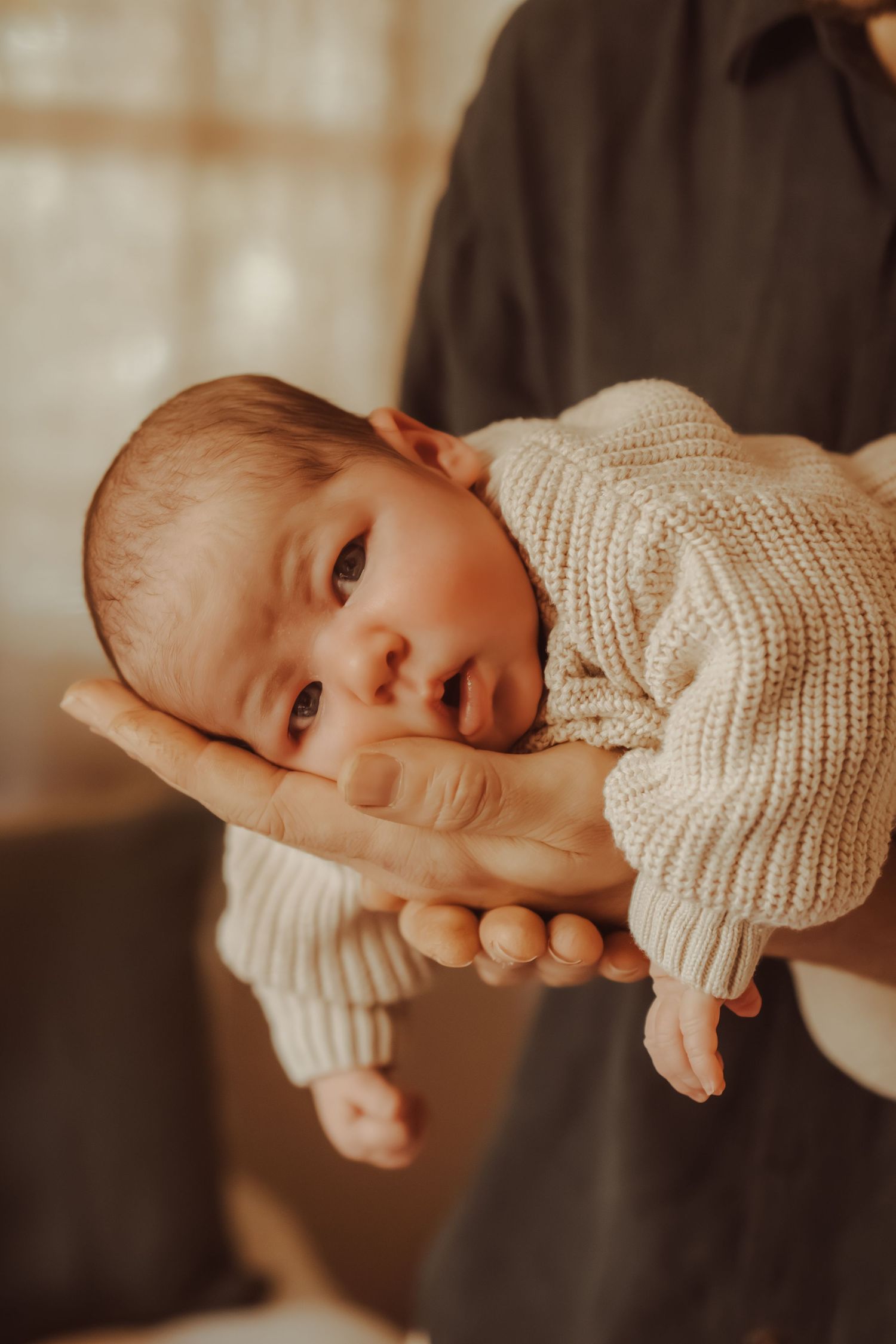 Close-up of baby wearing cream knit sweater in warm lighting.