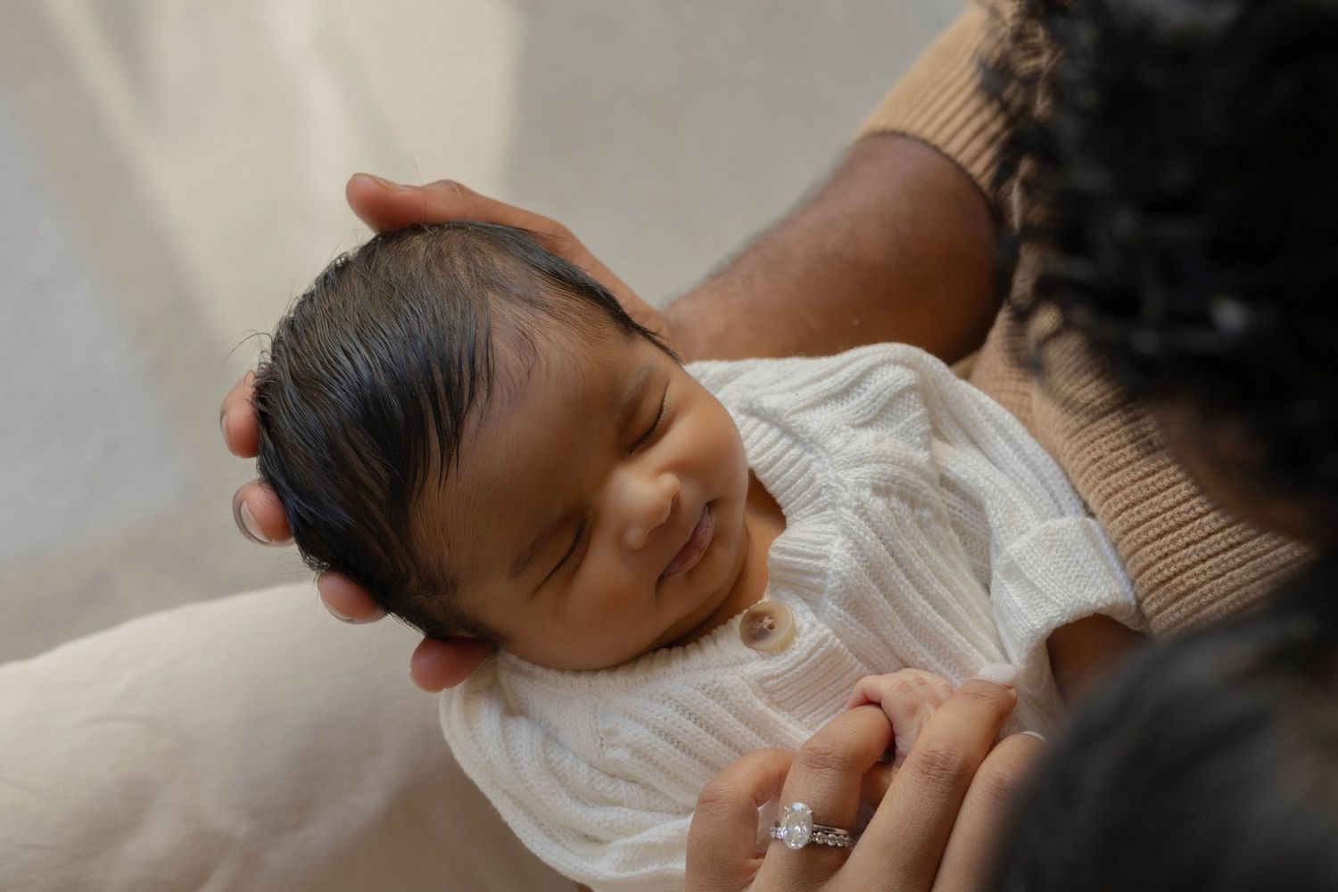 Baby resting peacefully on white bedding in natural light.