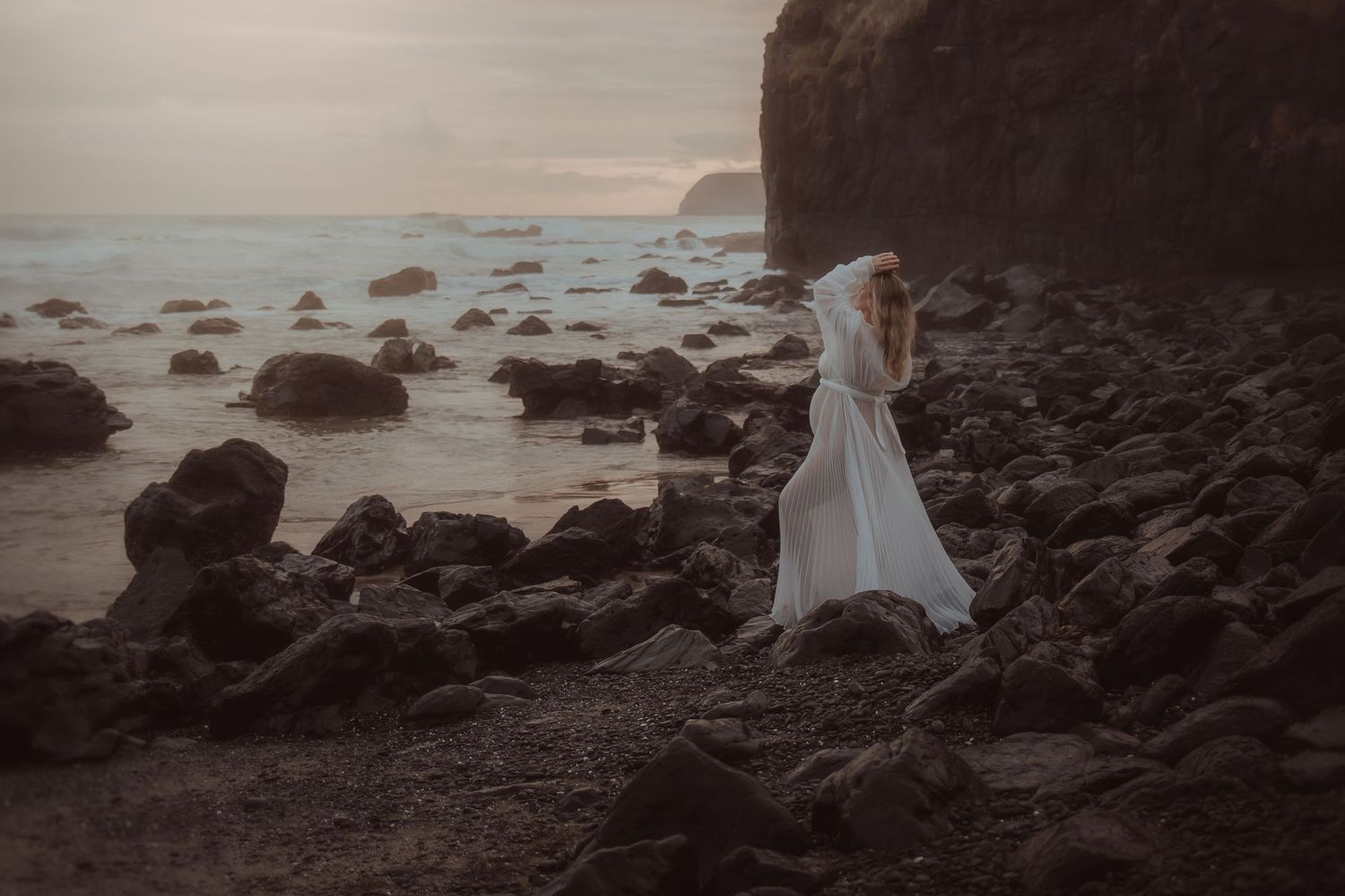 A minimalist coastal portrait with rocky shoreline and misty ocean backdrop.