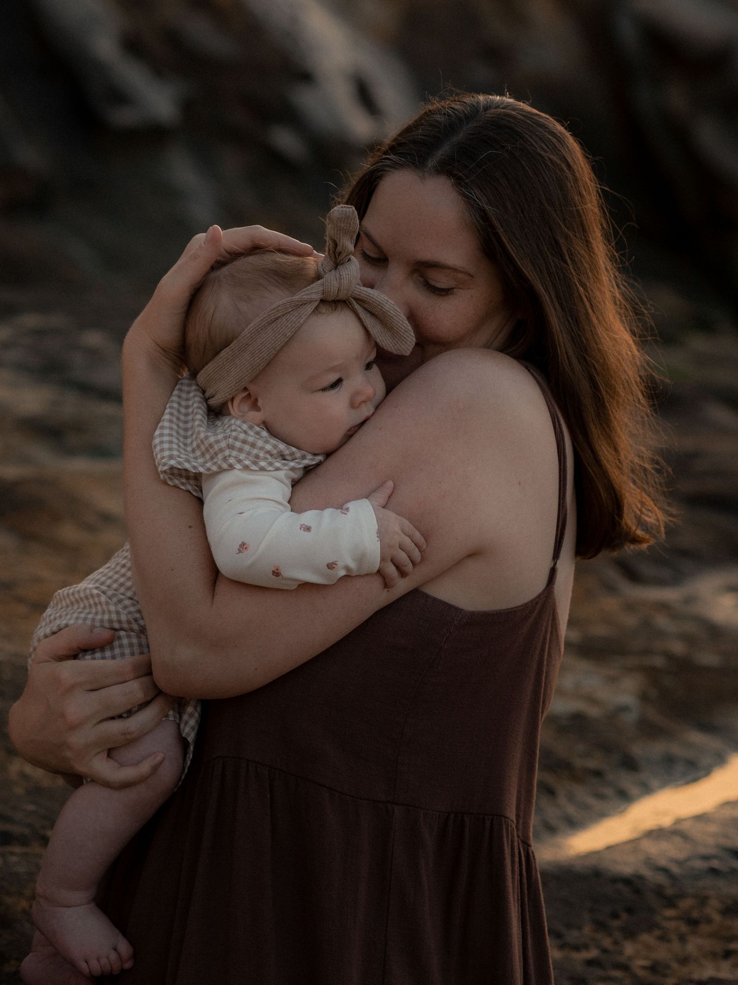 A parent and baby share tender moments in a series of intimate outdoor portraits at golden hour.