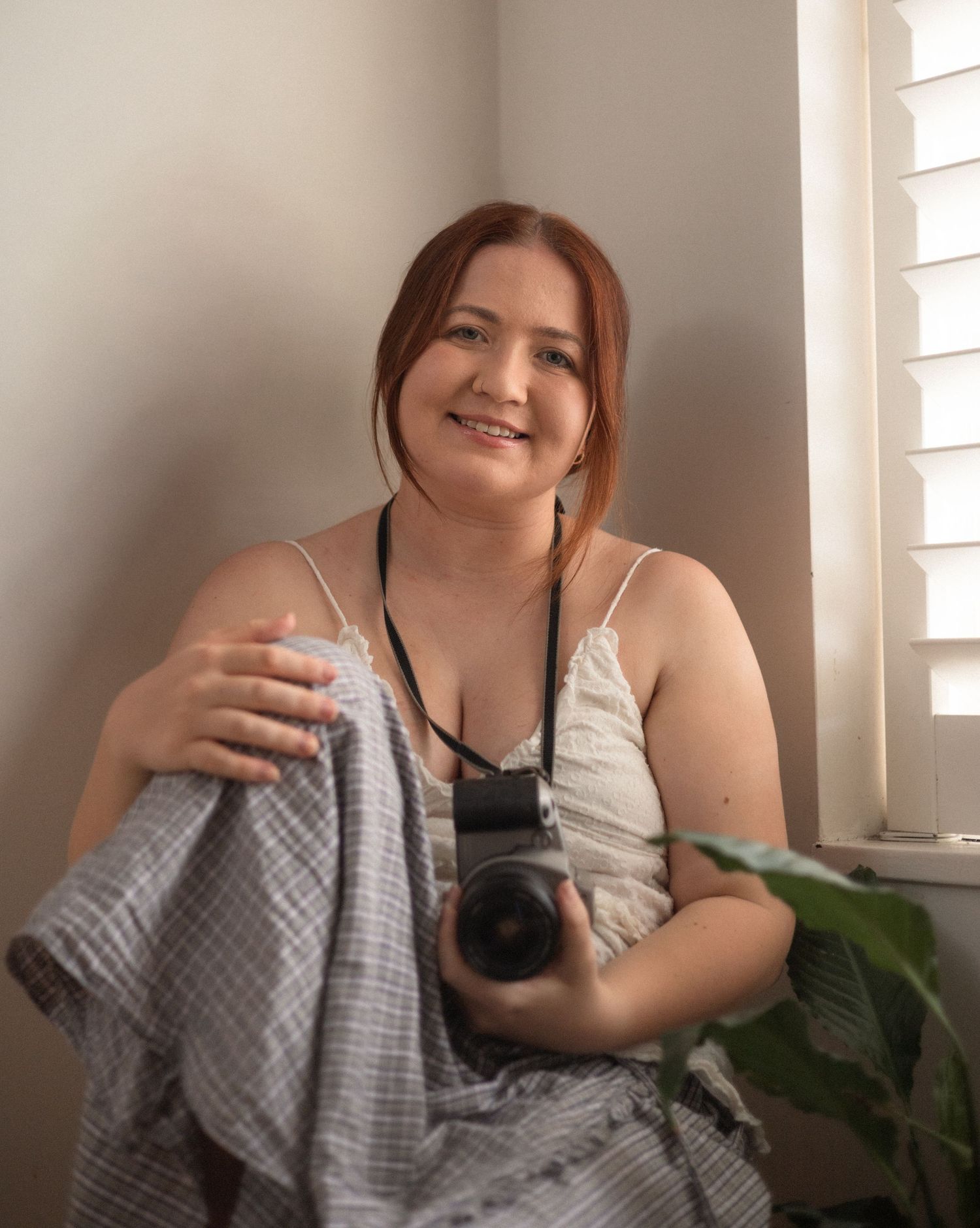 Indoor portrait session with natural window light and cozy blanket.