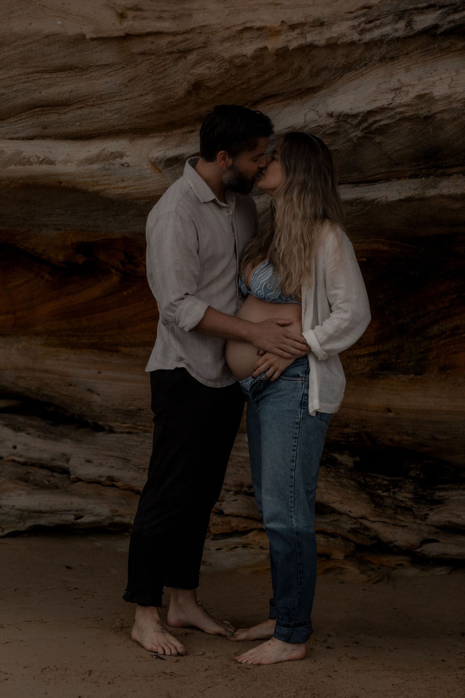 Romantic couple portraits captured in the shadows of a beach cave.