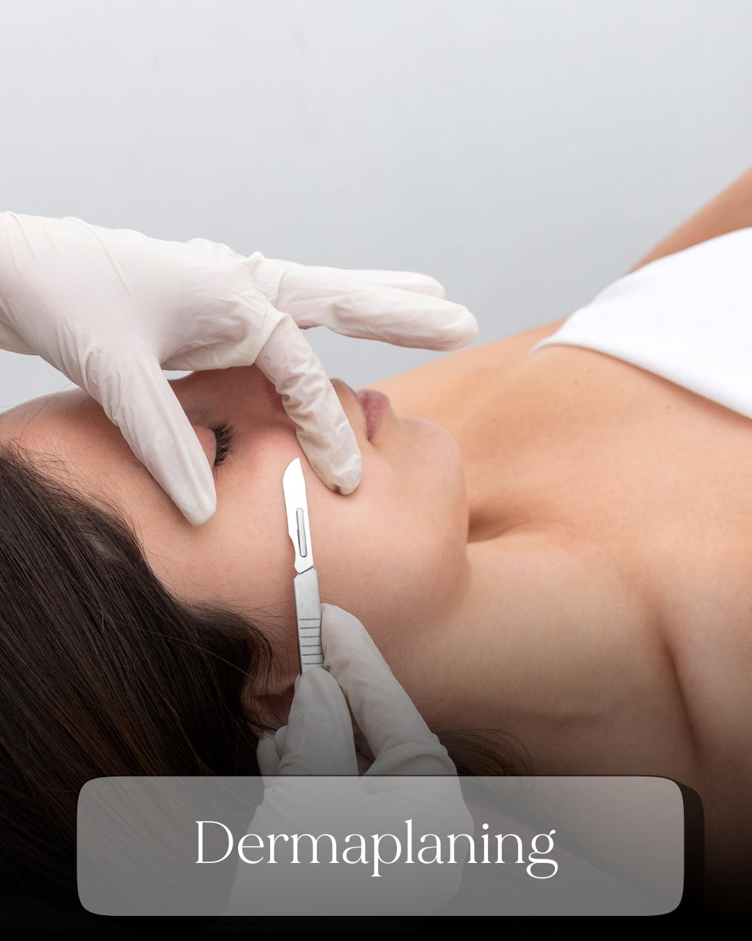 Close-up of a dermaplaning skincare treatment with a gloved esthetician using a scalpel on a womans face.