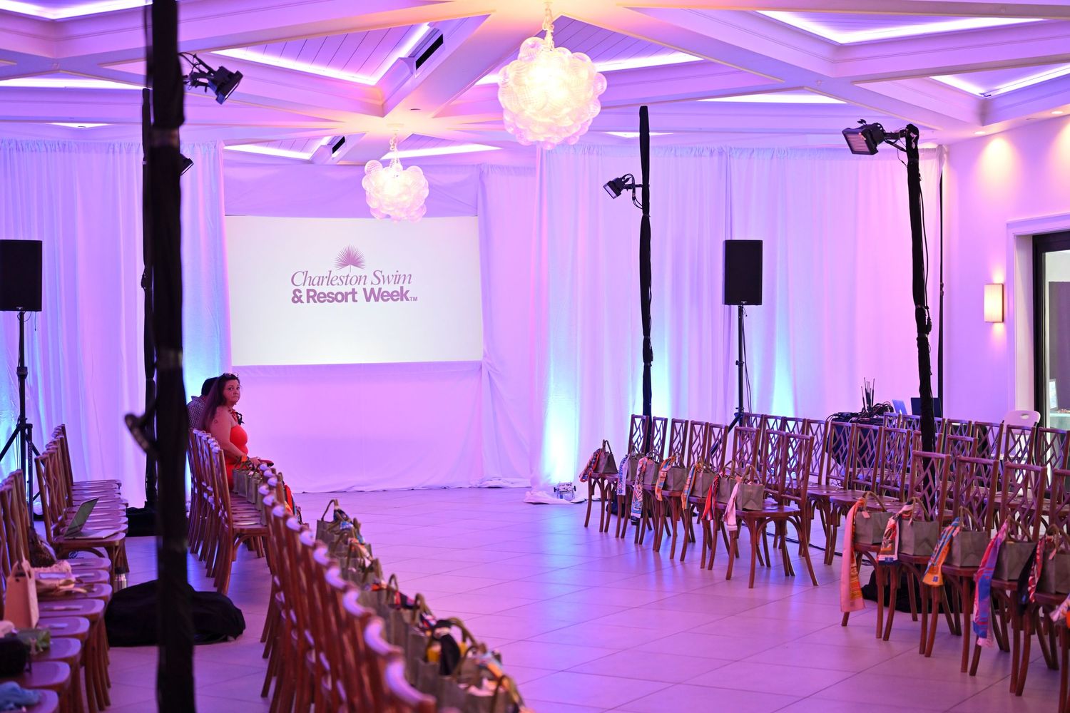 Elegant ballroom setup for Charlotte State Resort Week event with purple lighting, rows of chairs, and projection screen.