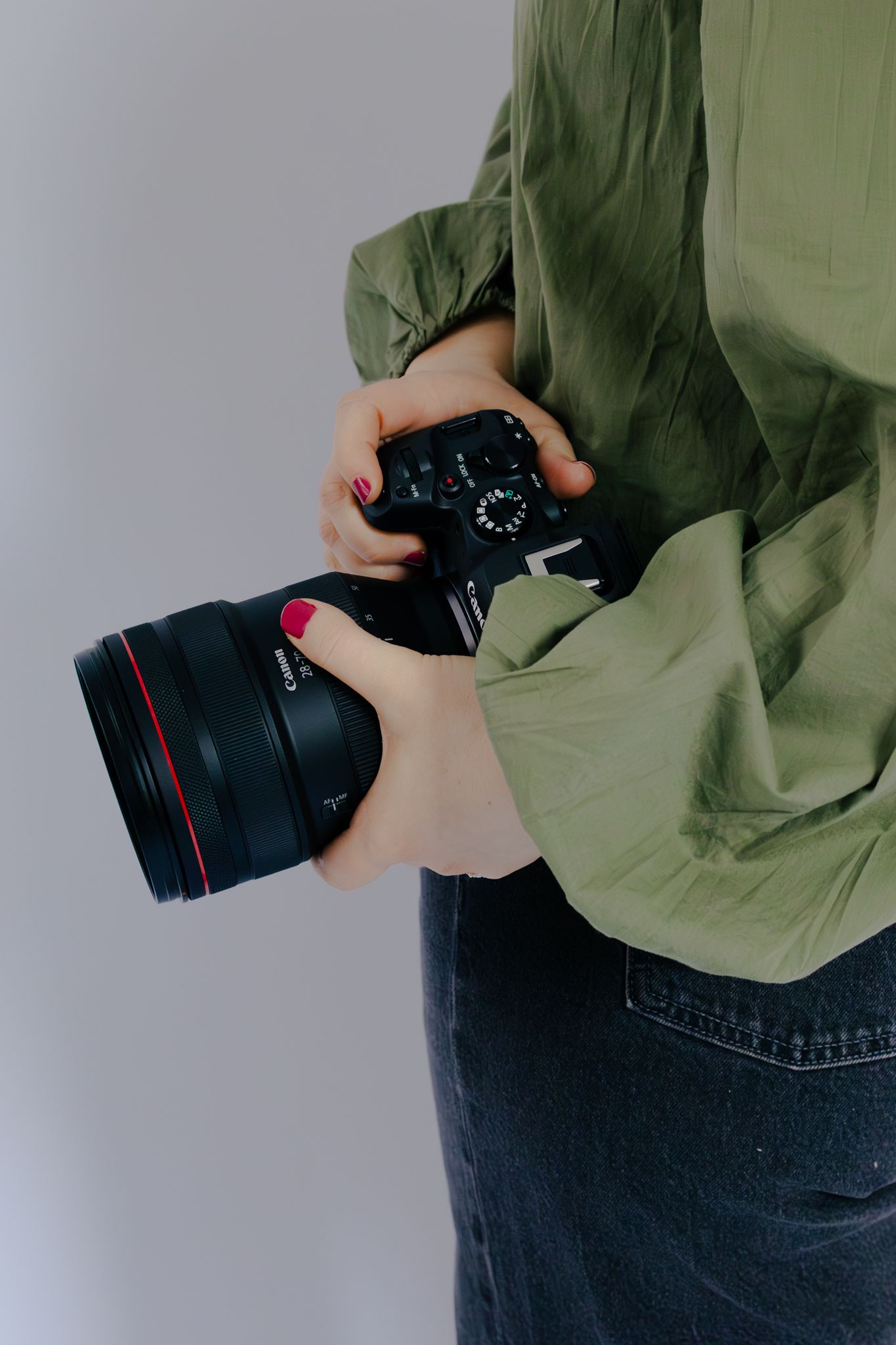 Close-up shots of hands holding professional camera lens against green clothing.