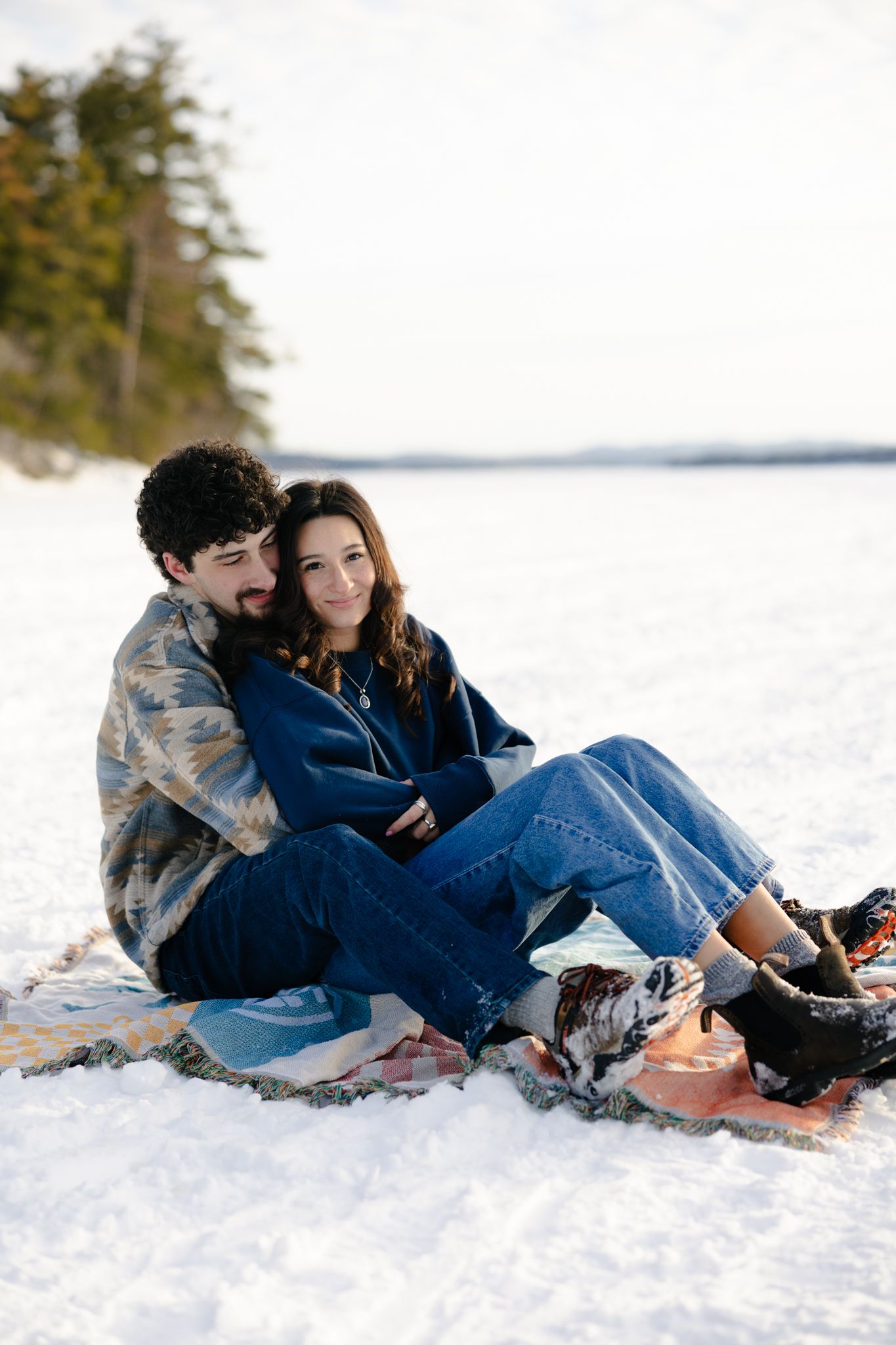 A couple sitting together on a snowy landscape during winter.