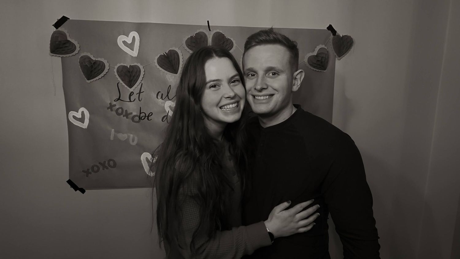 Black and white photo with heart decorations on a wall.
