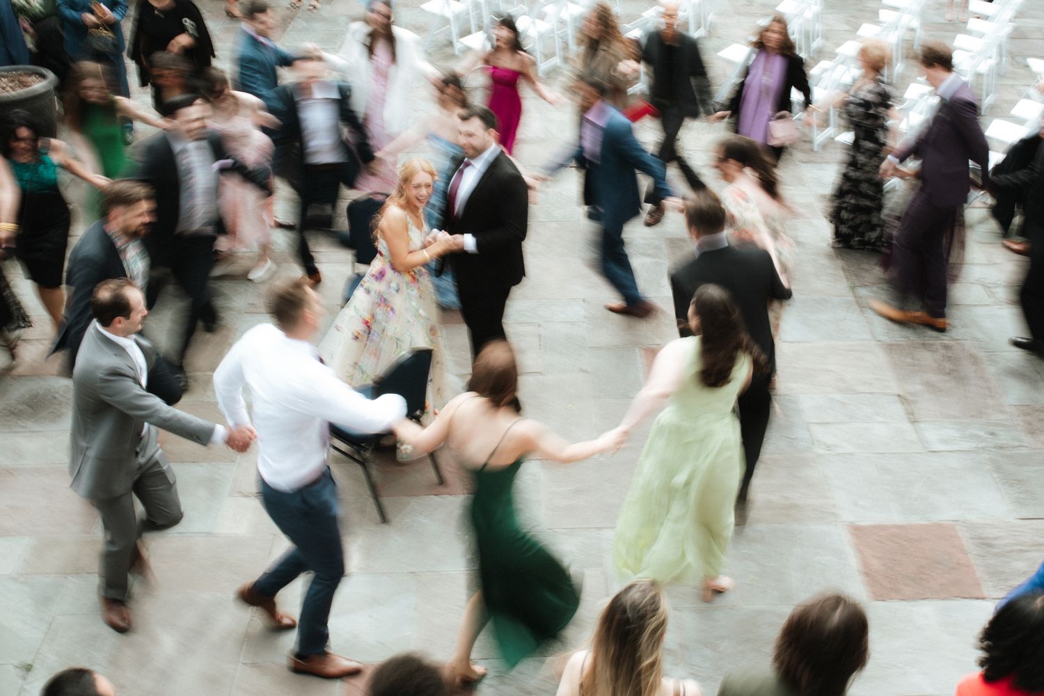 A large group of people dancing together in a social dance setting on a light colored floor.