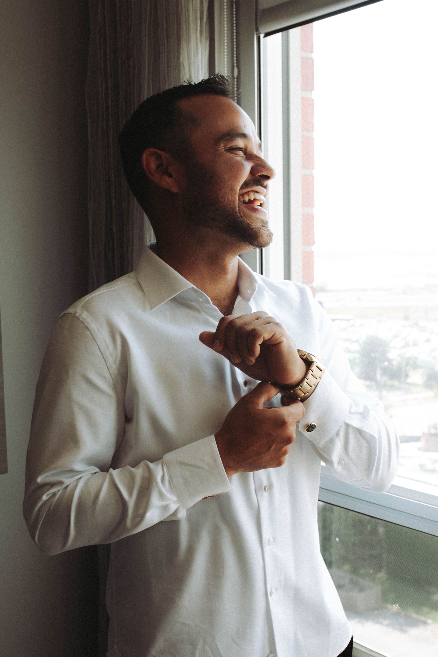 A person in a white dress shirt adjusts their collar while standing by a window in a series of connected photos.