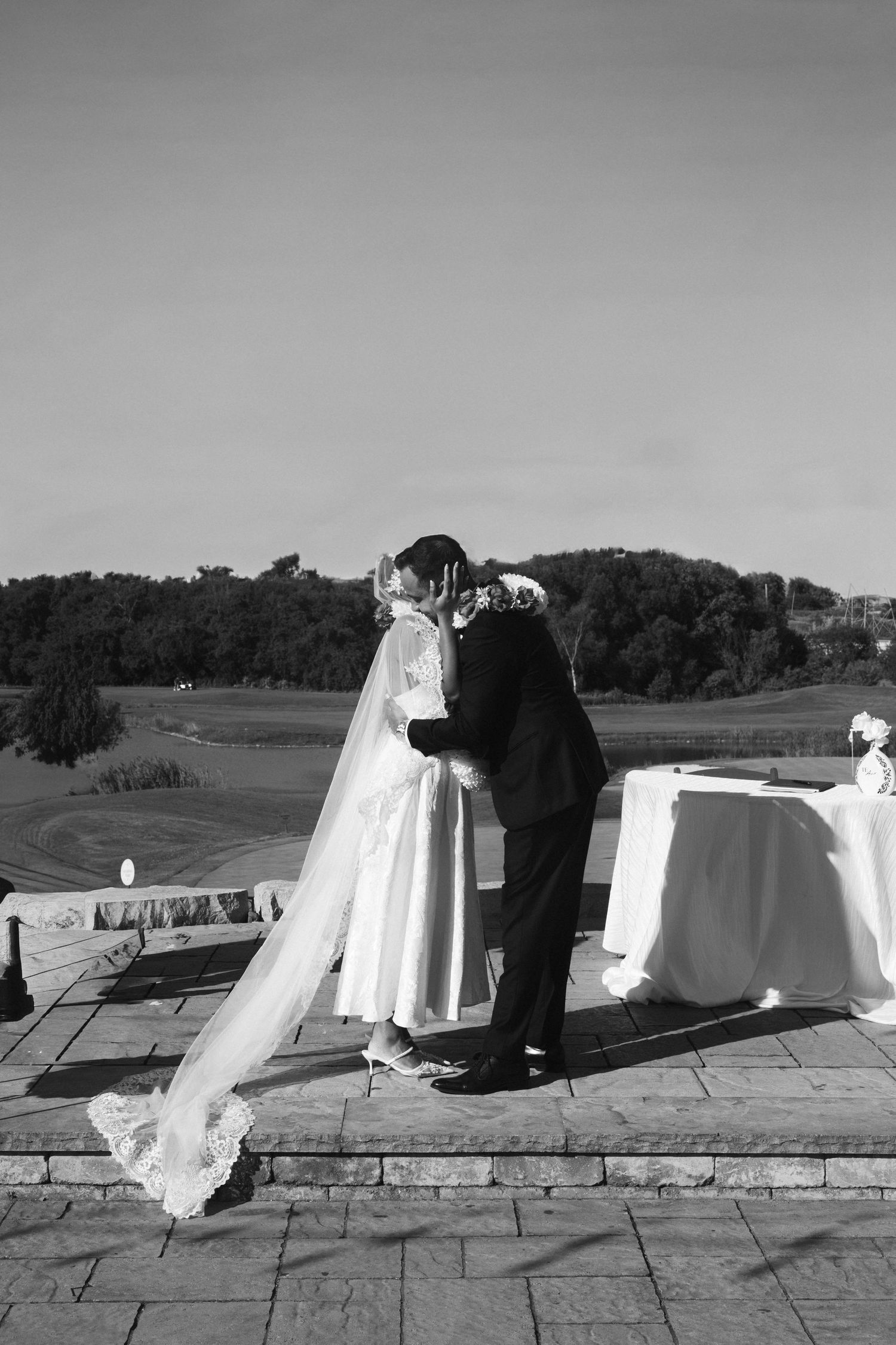 A sequence of black and white photos showing a wedding dress train laid out on stone pavement outdoors.