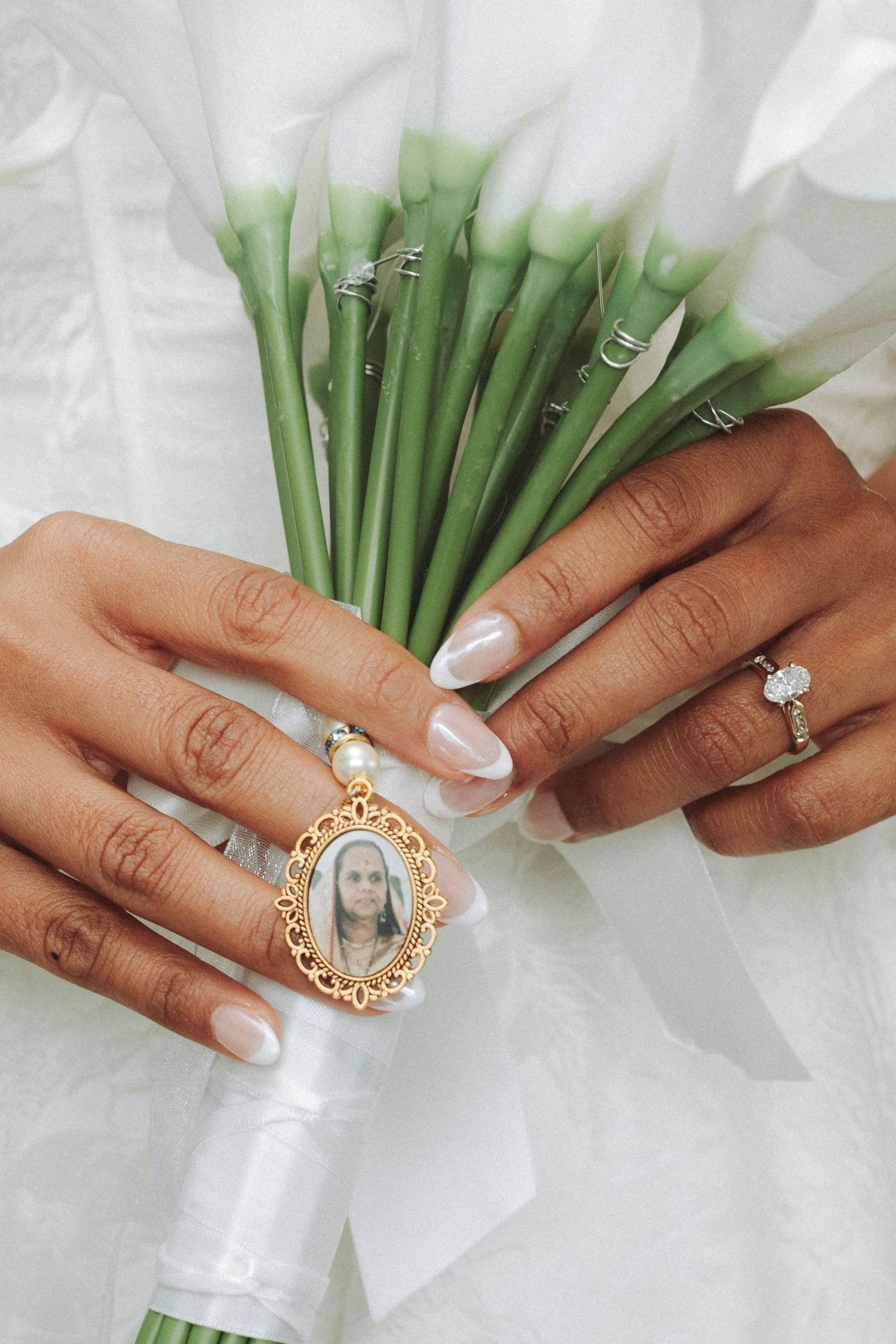 Wedding ring detail shots showing hands holding white flowers with various engagement rings and jewelry against white fabric.