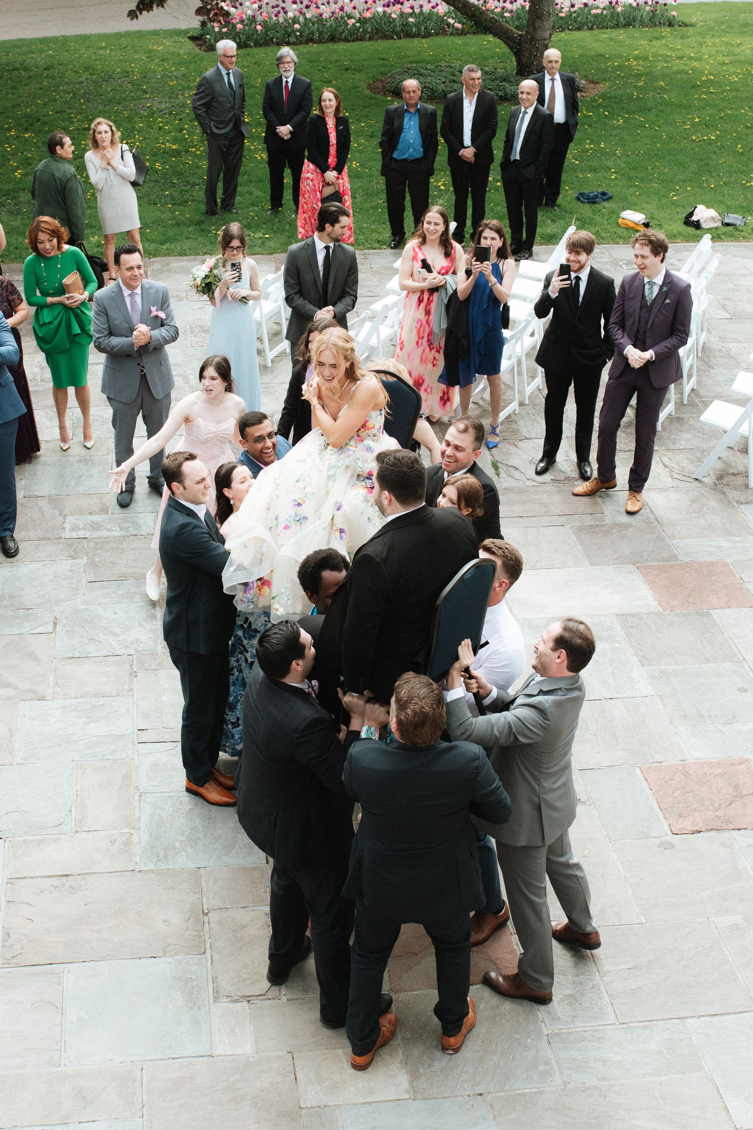 Wedding guests gather in small groups on an outdoor stone patio during a celebration reception.