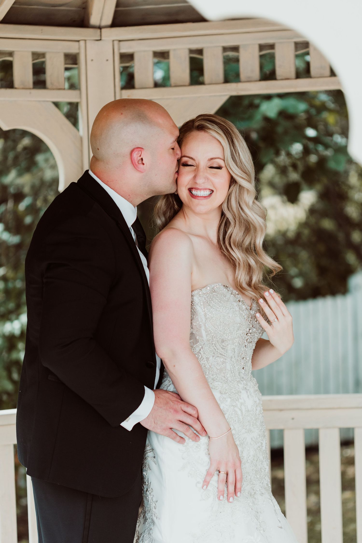 A romantic wedding couple shares intimate moments together in a white gazebo on their special day.