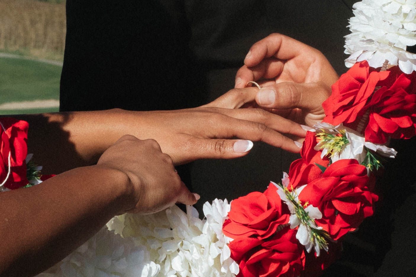 Hands carefully arrange vibrant red and white silk flowers in a decorative pattern.