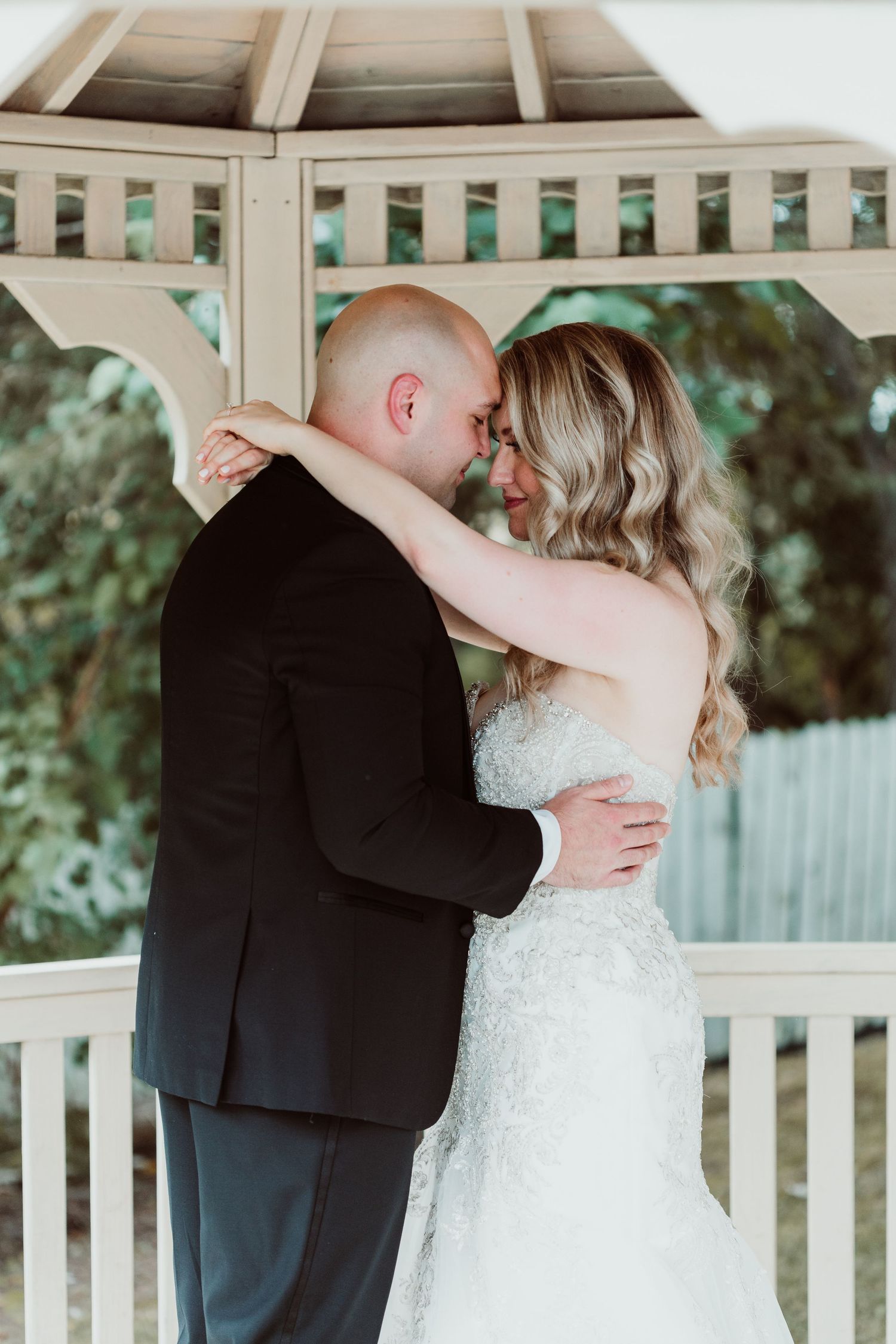 Romantic wedding couple sharing intimate moments in a white gazebo during their special day.