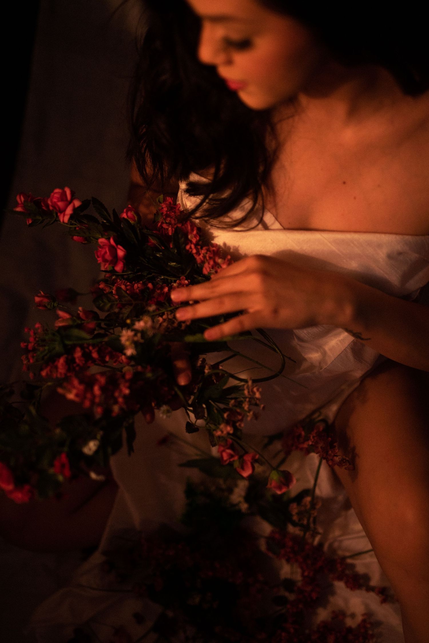 A dark and moody artistic portrait series with pink flowers and soft lighting creates an intimate atmosphere.