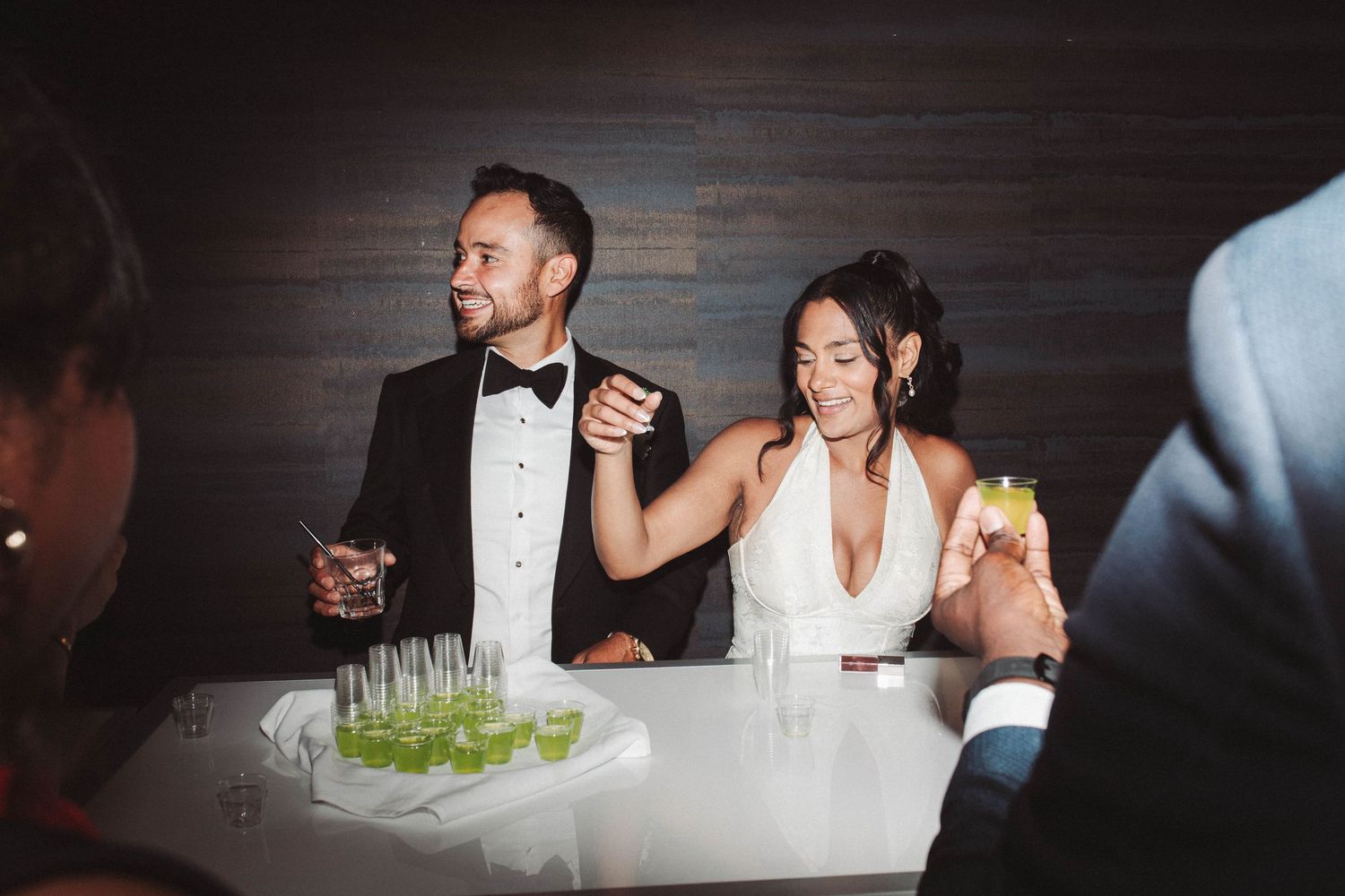 Wedding guests enjoy a lively reception celebration at an elegant indoor venue with ambient lighting.