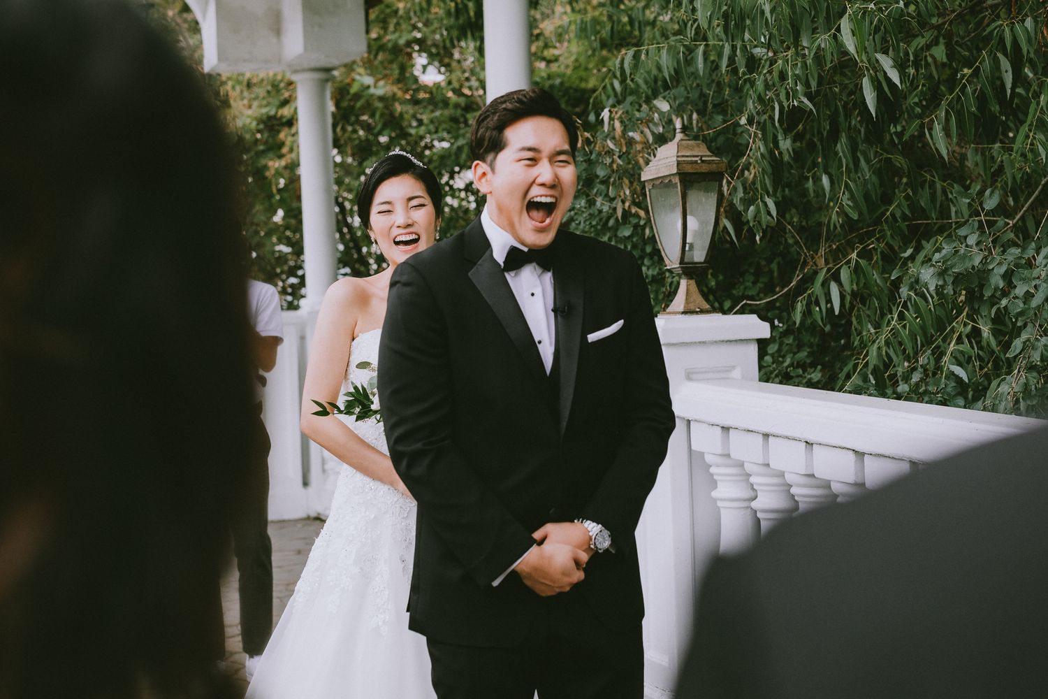 A couple shares joyful moments together during their wedding photoshoot in a lush garden setting.