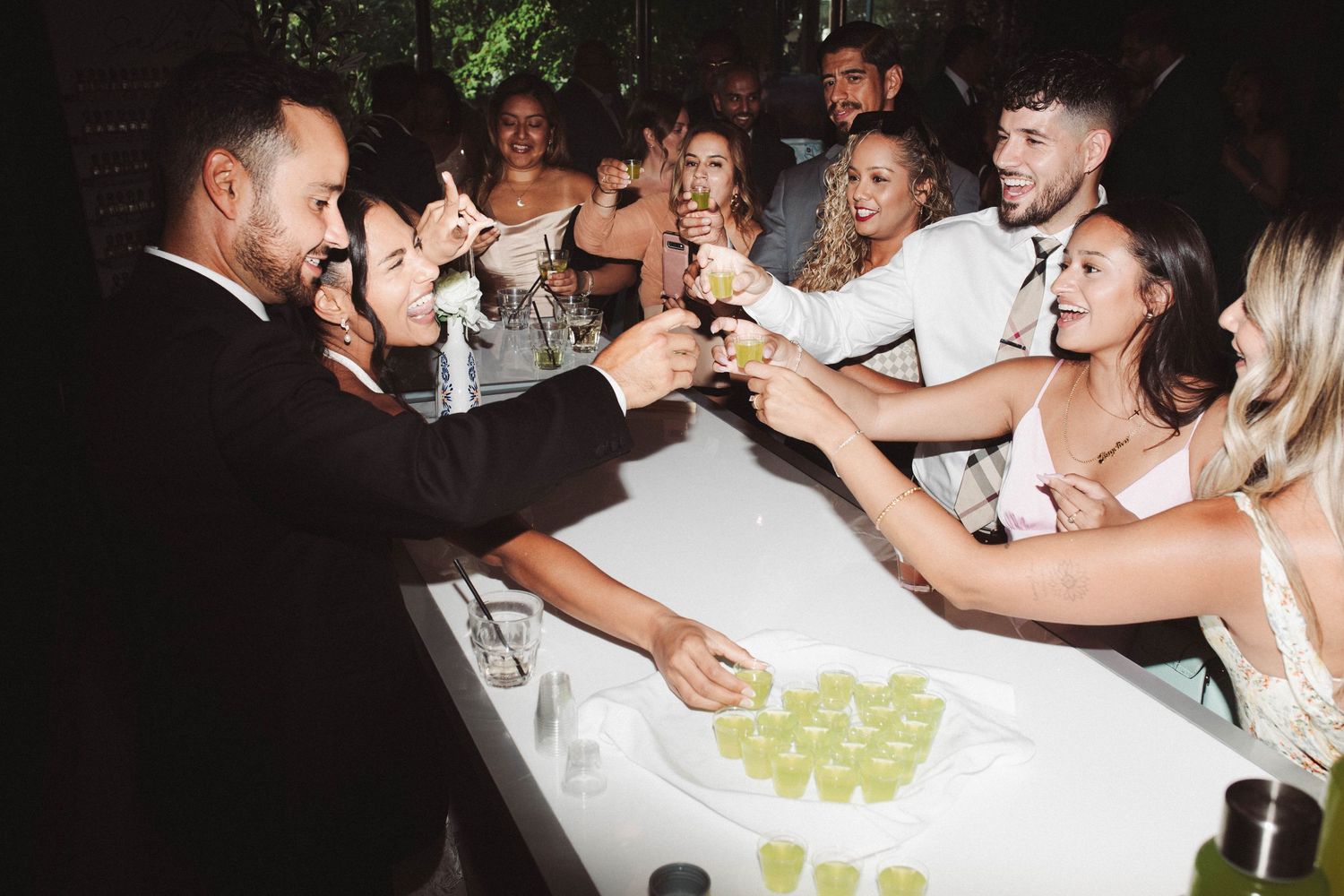 Wedding guests enjoying drinks and dancing together at a lively reception celebration.