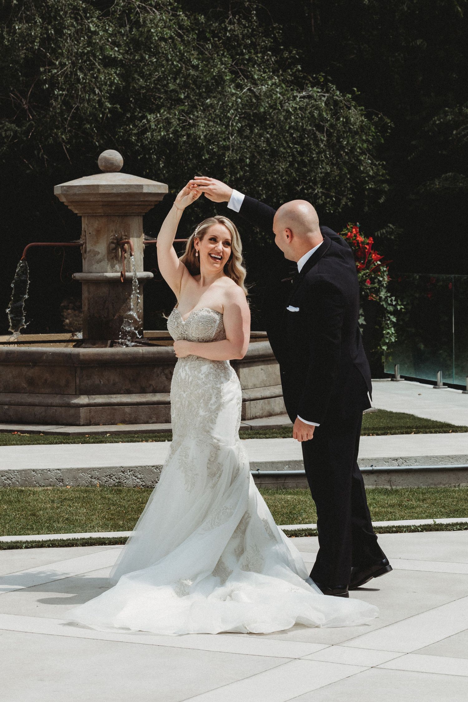 A romantic first dance sequence between newlyweds on an outdoor patio with stone pillars and greenery in the background.
