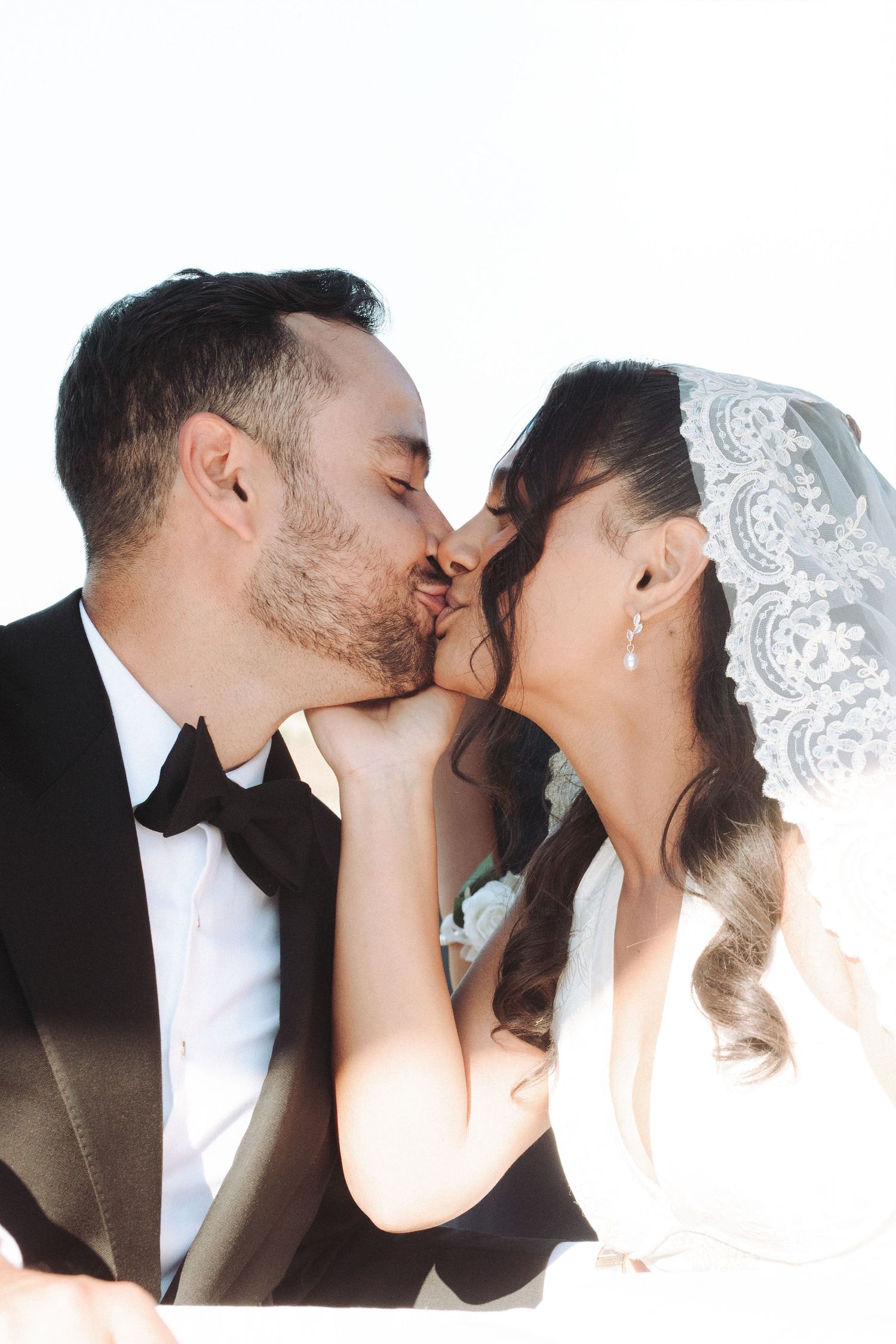 A romantic series of four wedding photos showing a couple sharing intimate kisses under a white veil.
