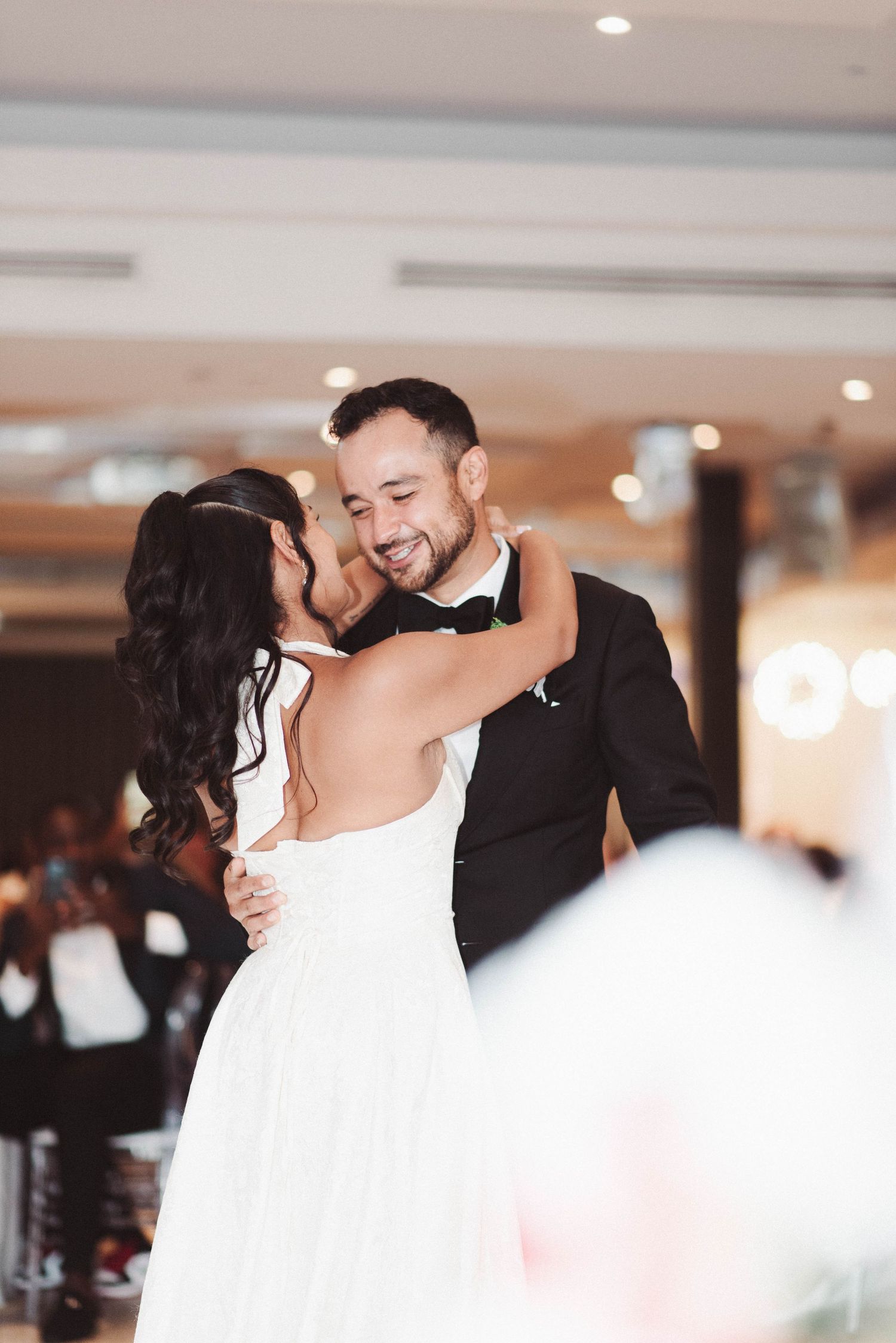 A couple shares an intimate first dance at their wedding reception, with the bride in white and groom in black.