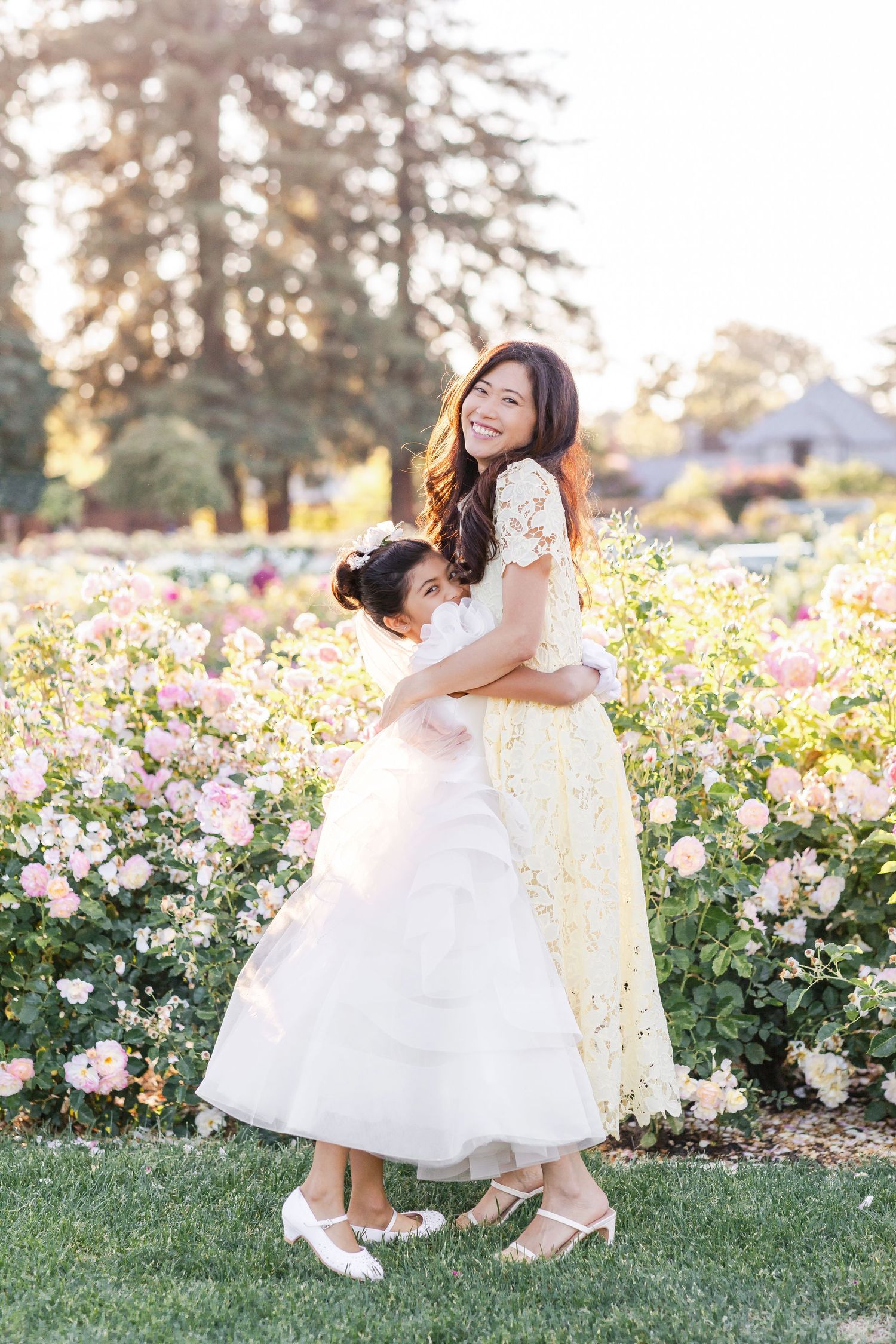 Mother and daughter share tender moments in a blooming rose garden at sunset.