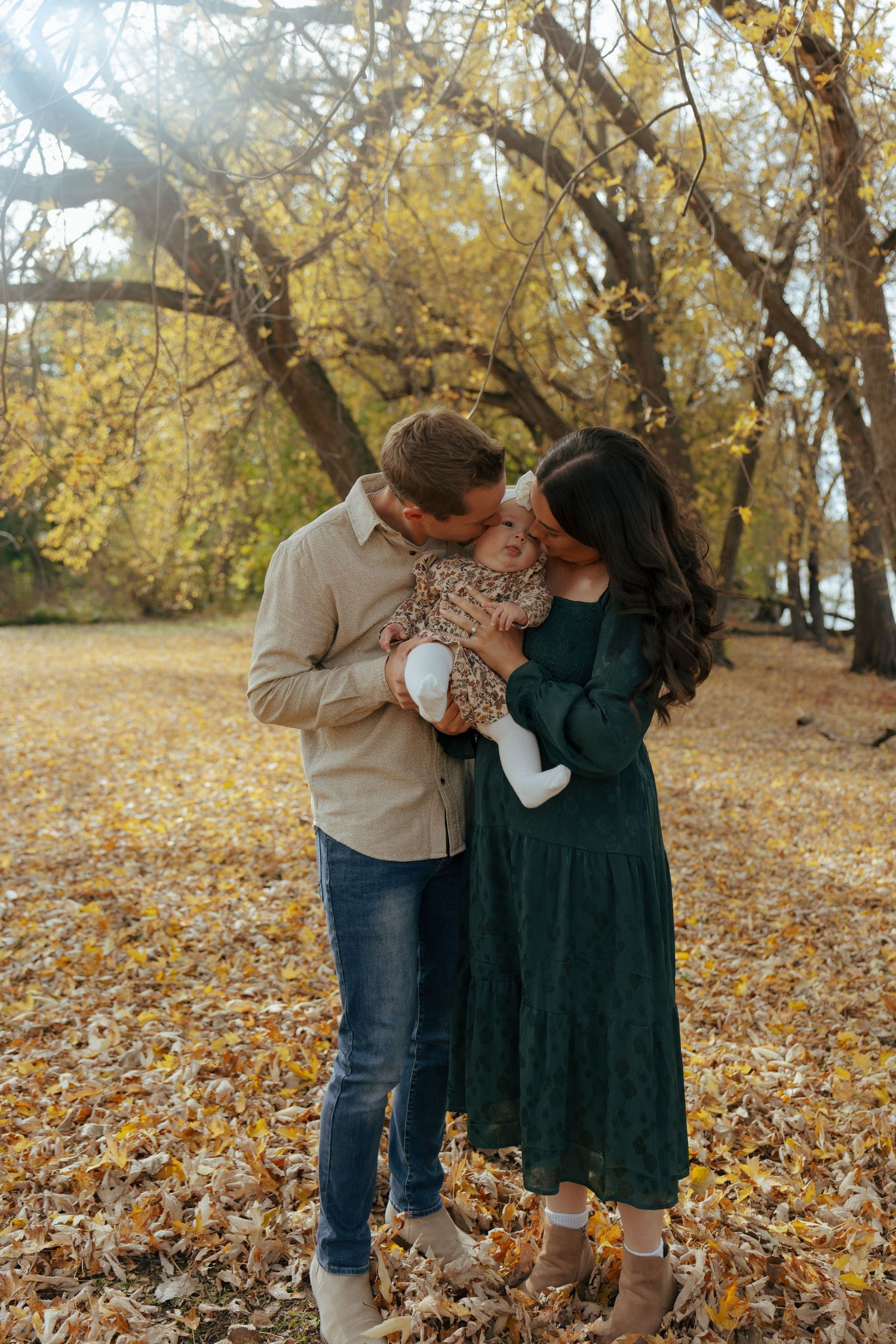 Couple sharing intimate moment among autumn trees with fallen leaves.